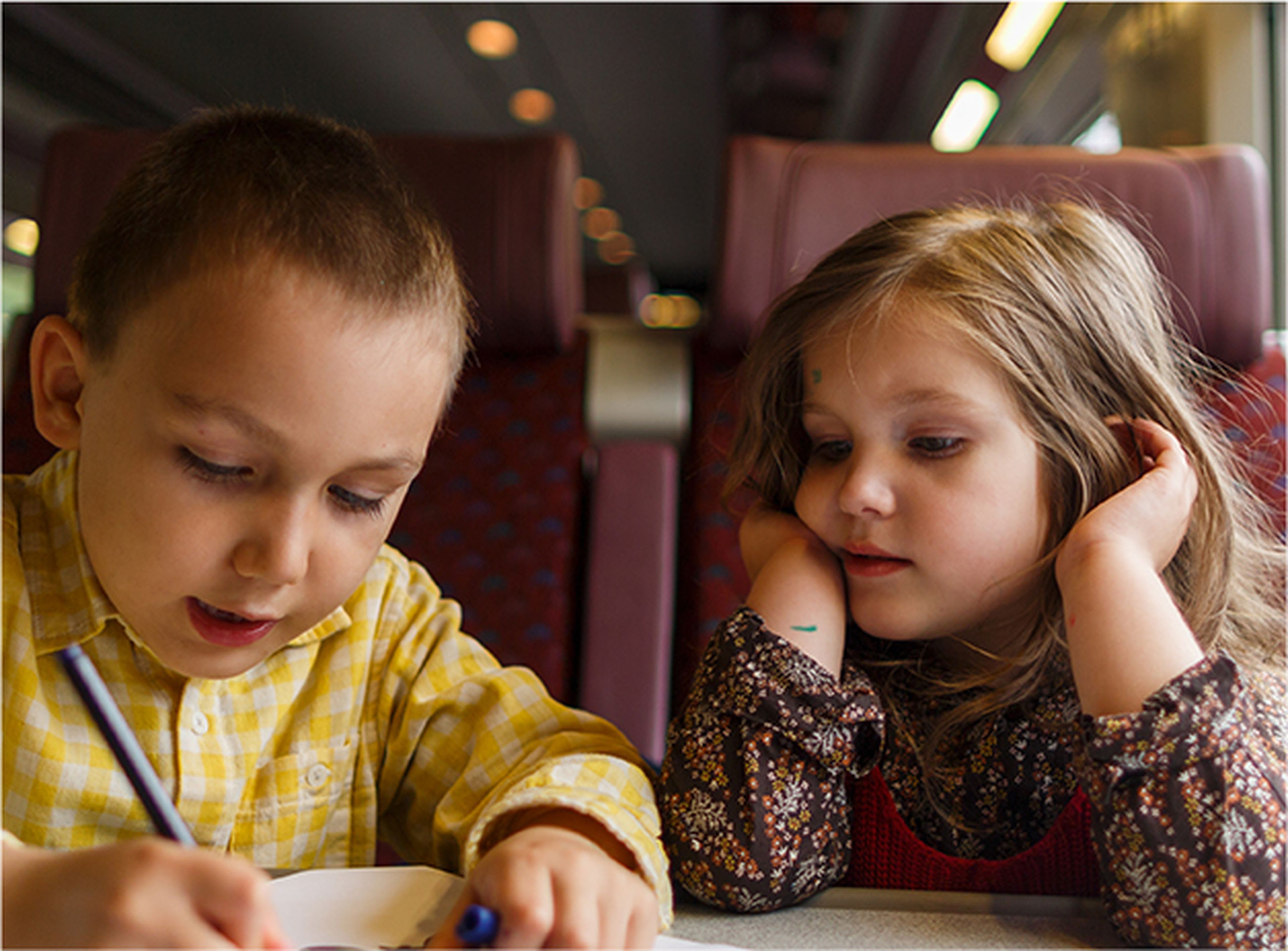 Un niño y una niña viajan en tren.