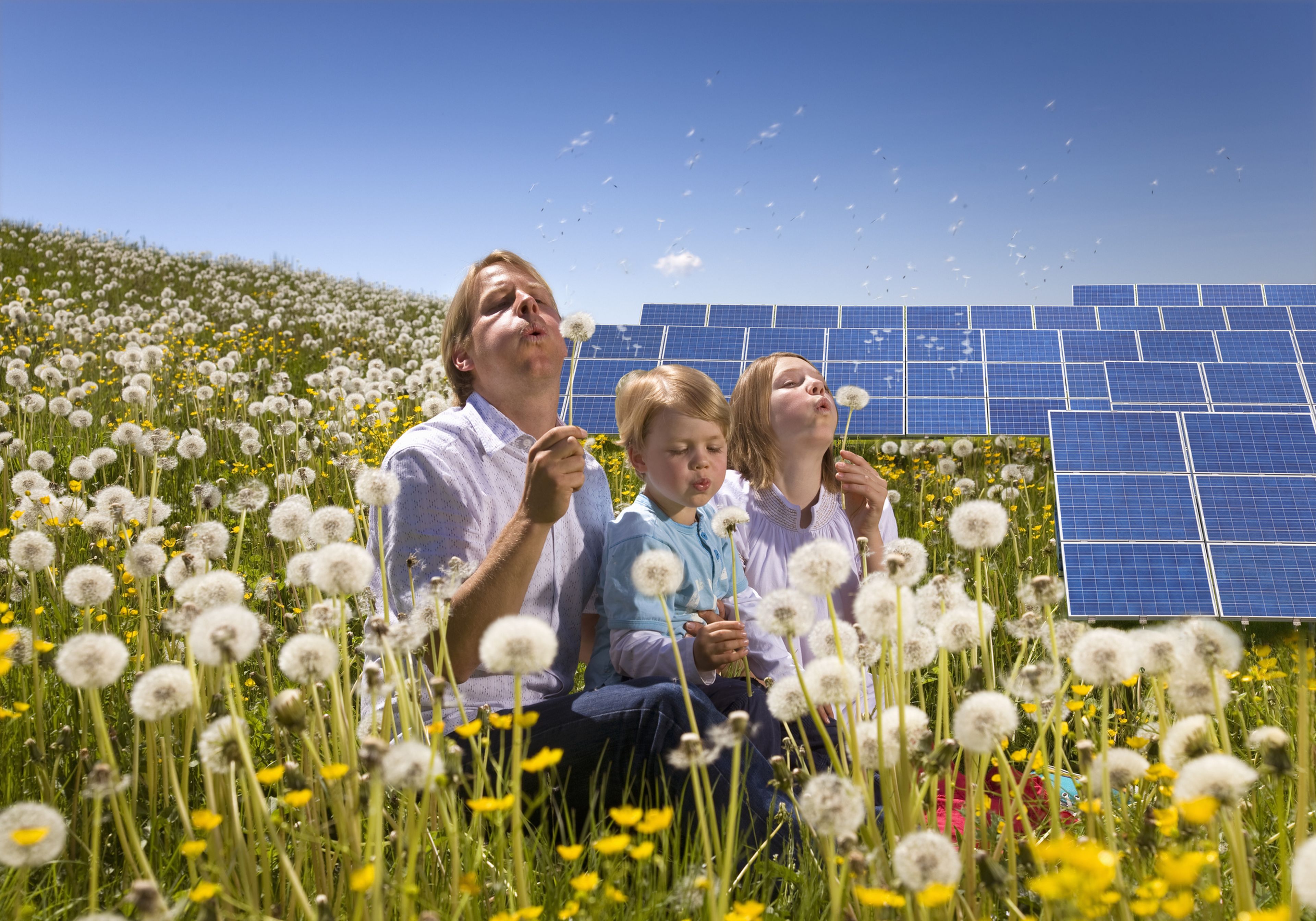 Un padre, su hija y su hijo junto a una instalación de placas solares.