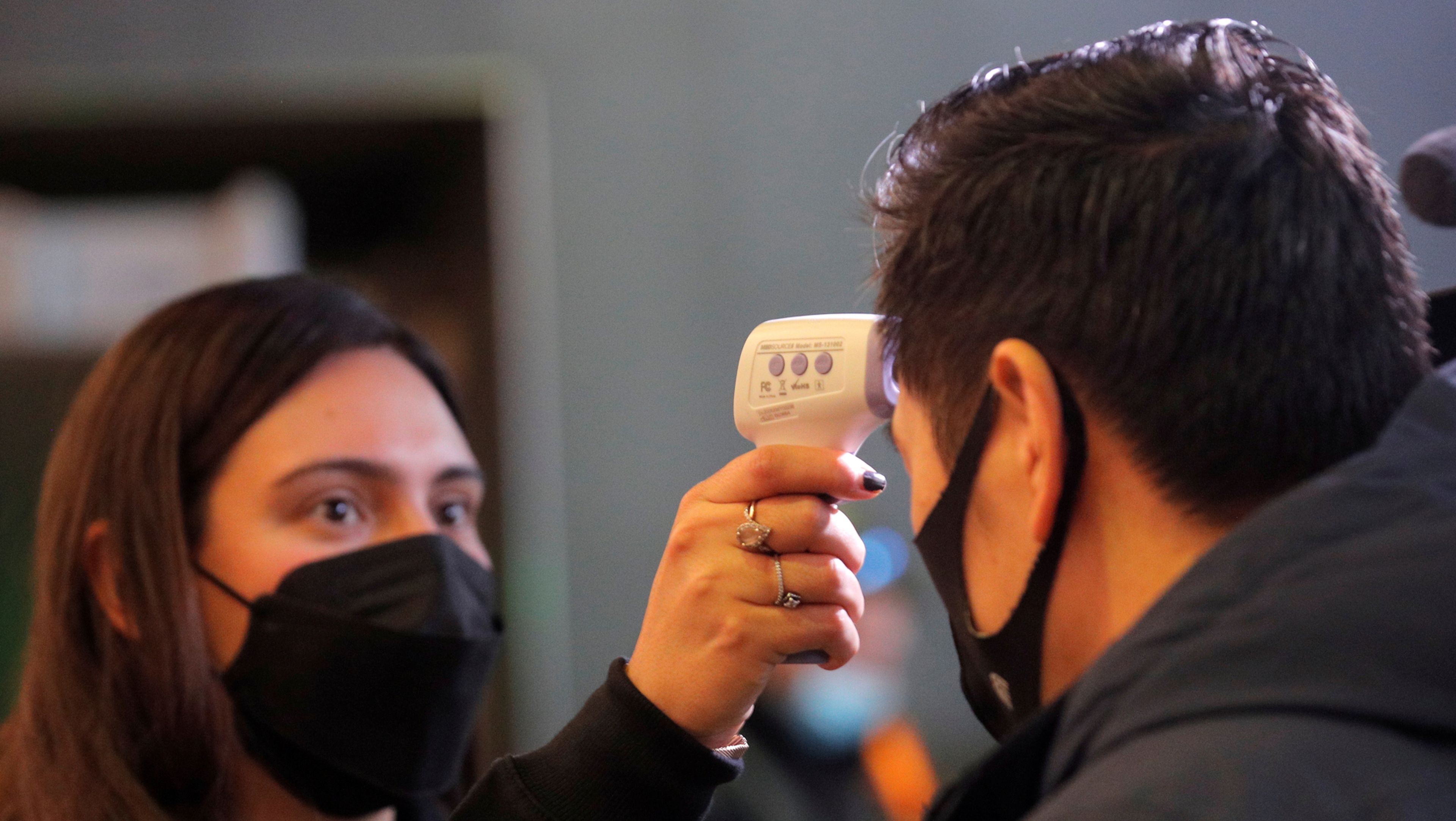 Una trabajadora controla la temperatura de un asistente a un evento en Nueva York