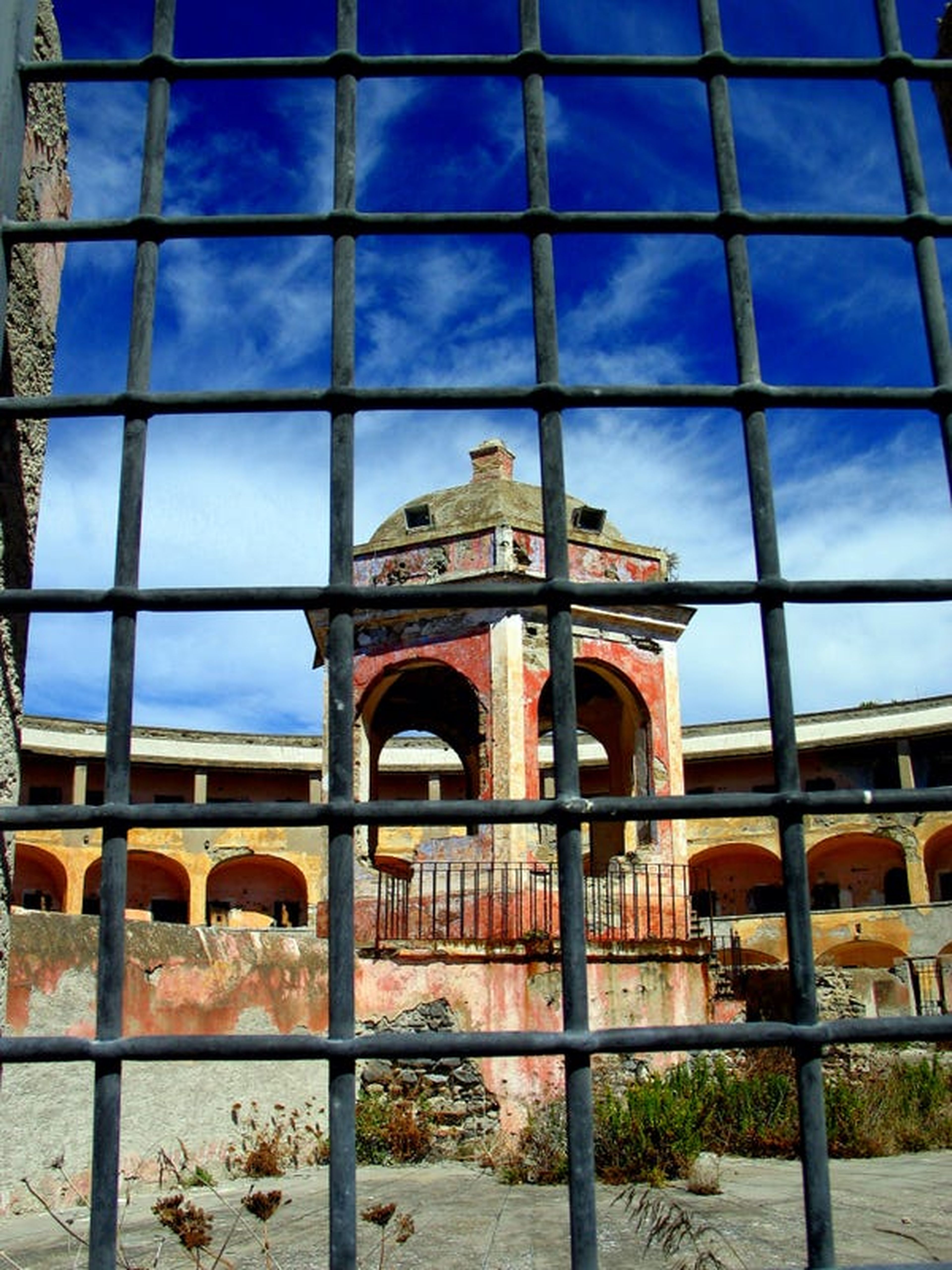 Vista a través de una ventana de rejilla hacia el patio de la prisión.