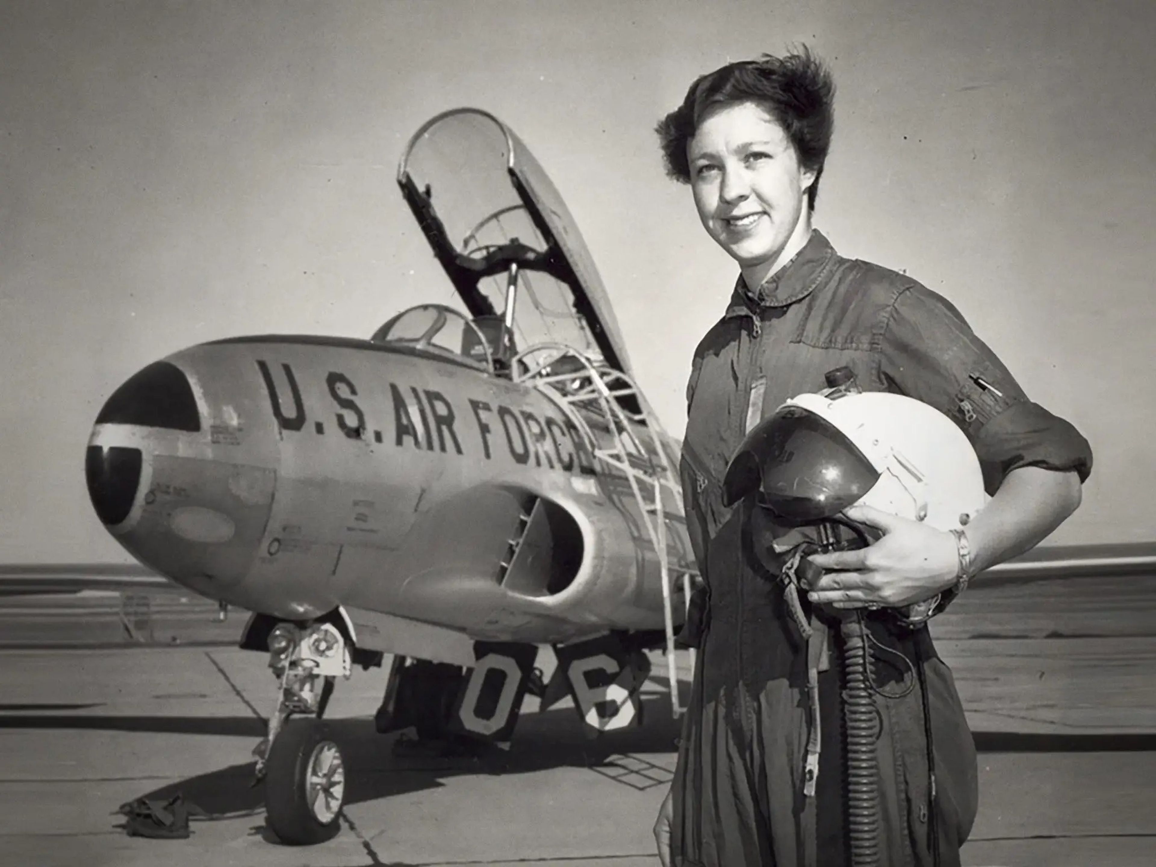 Wally Funk holds a helmet and stands by a US Air Force airplane