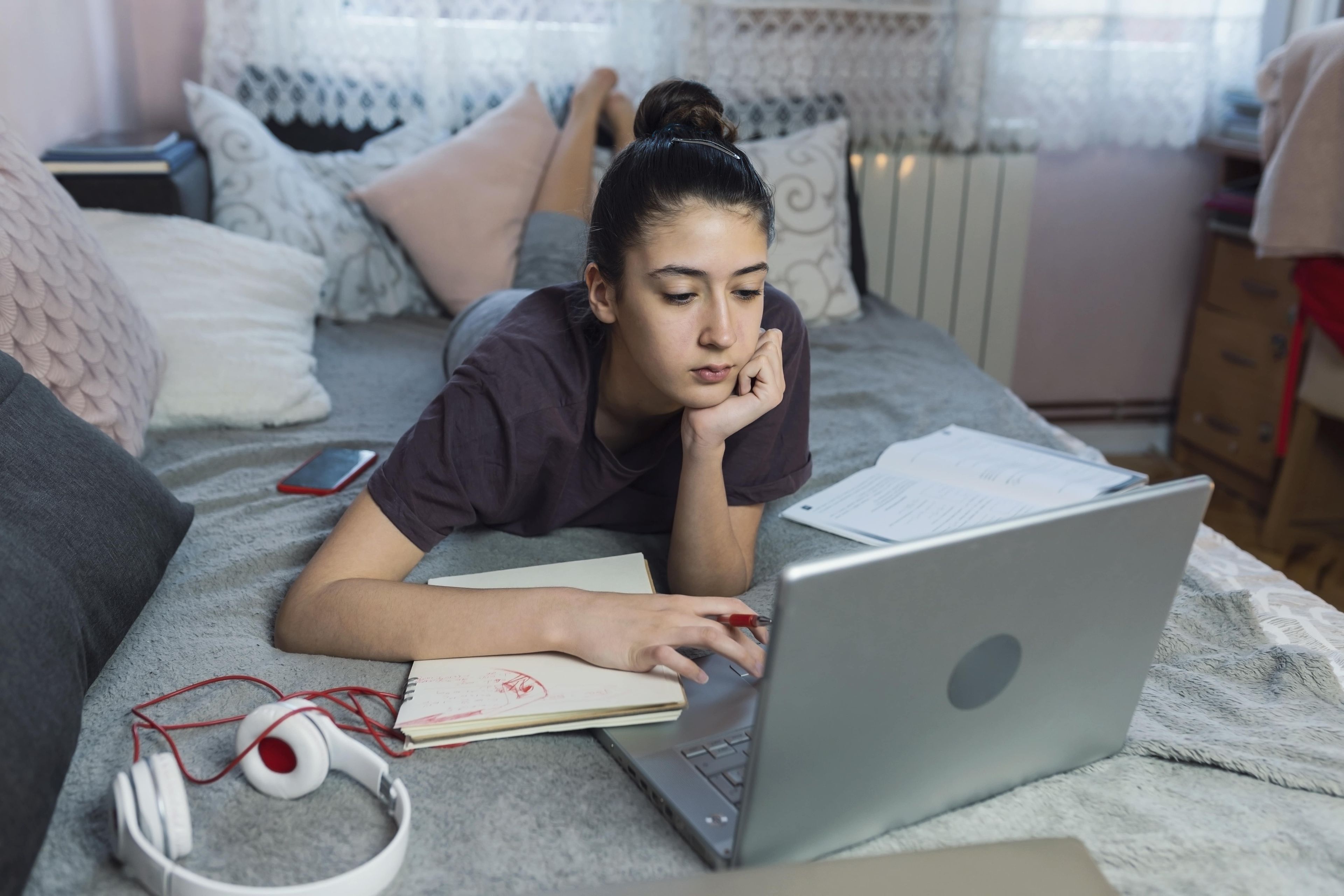 Una adolescente estudiando en la cama