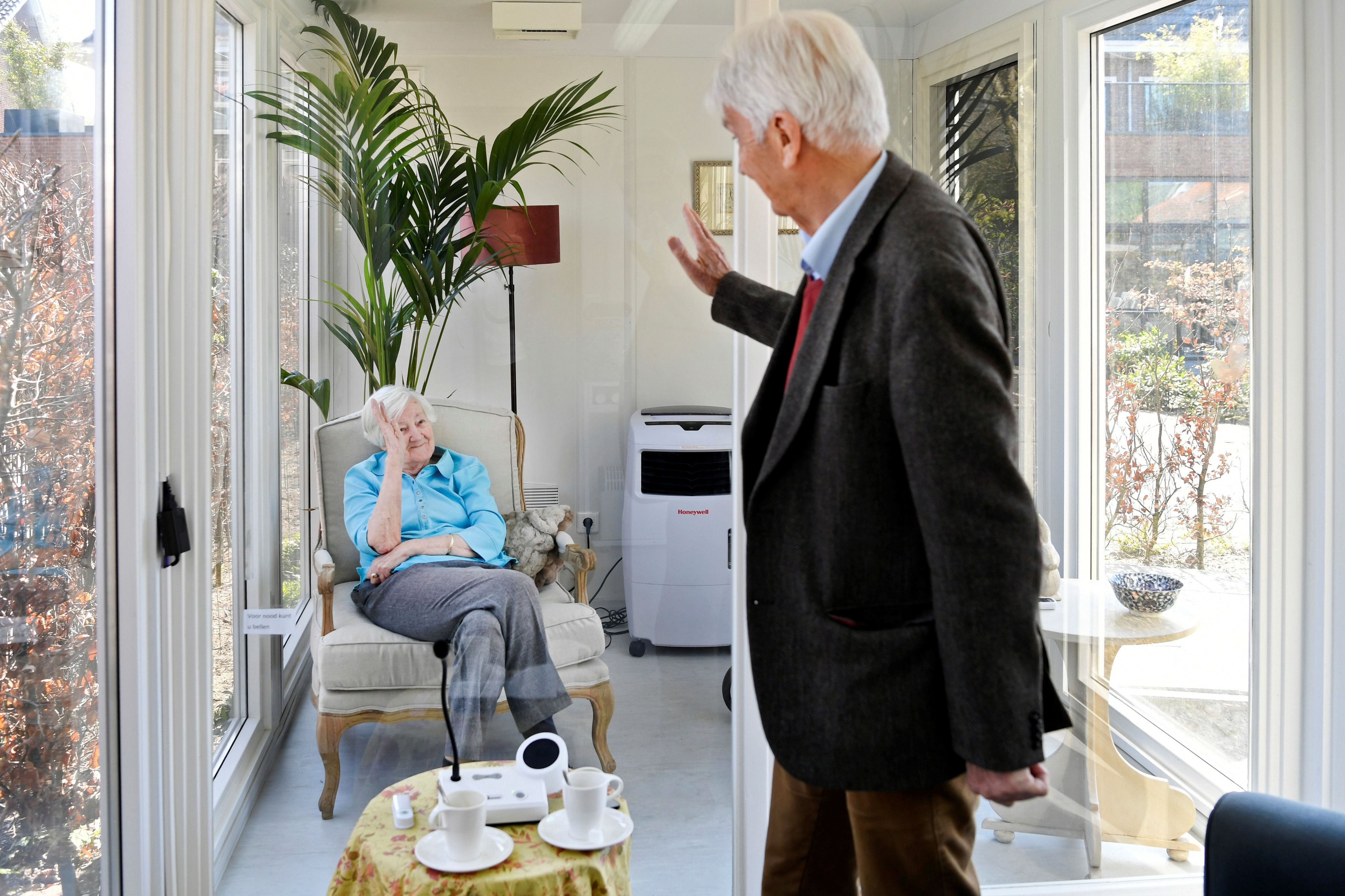 Un hombre visita a su esposa en un centro de atención para personas mayores con demencia, en una casa de cristal por el COVID-19.