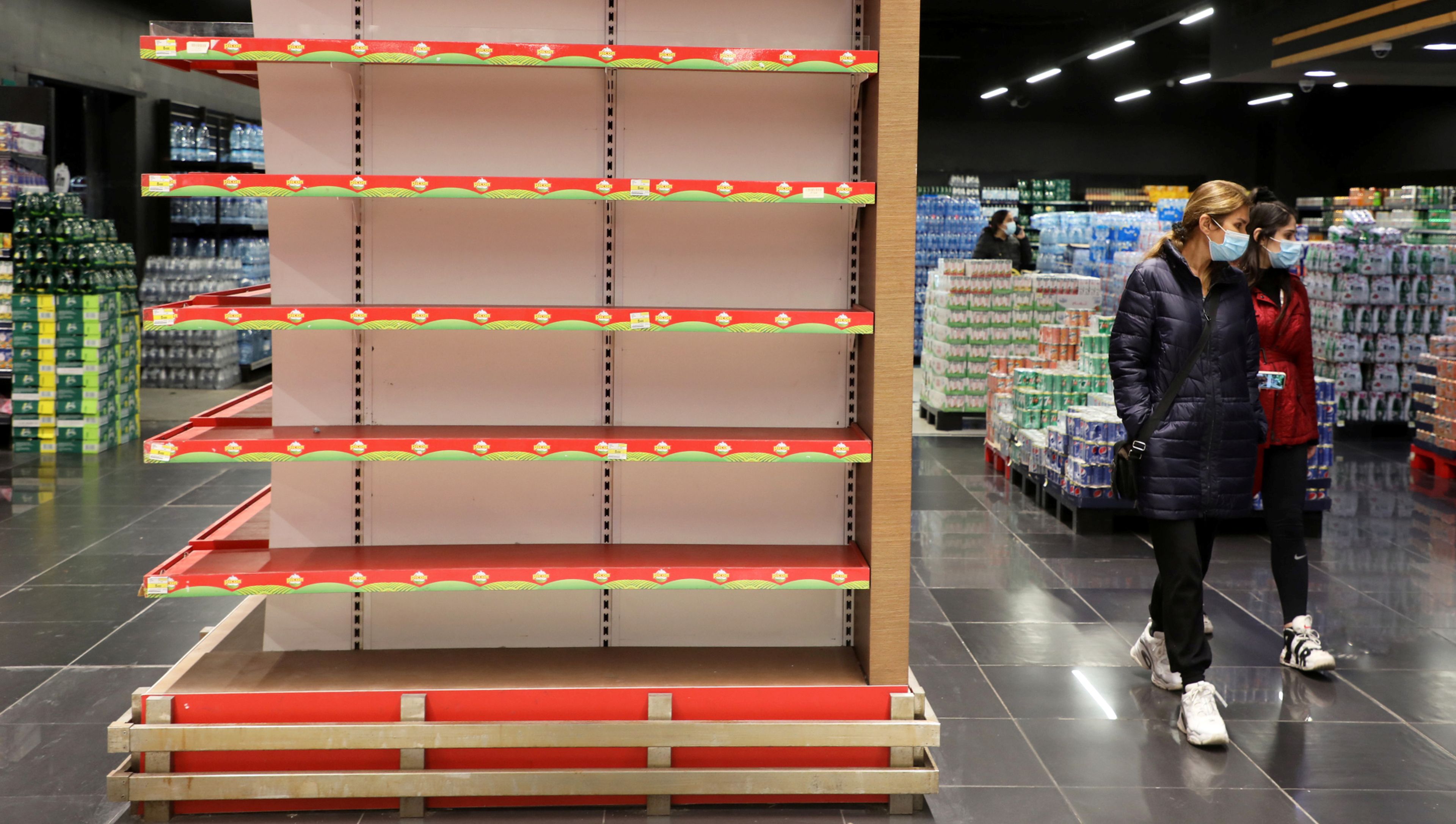 Dos mujeres pasean por un supermercado con las estanterías vacías durante la pandemia de coronavirus