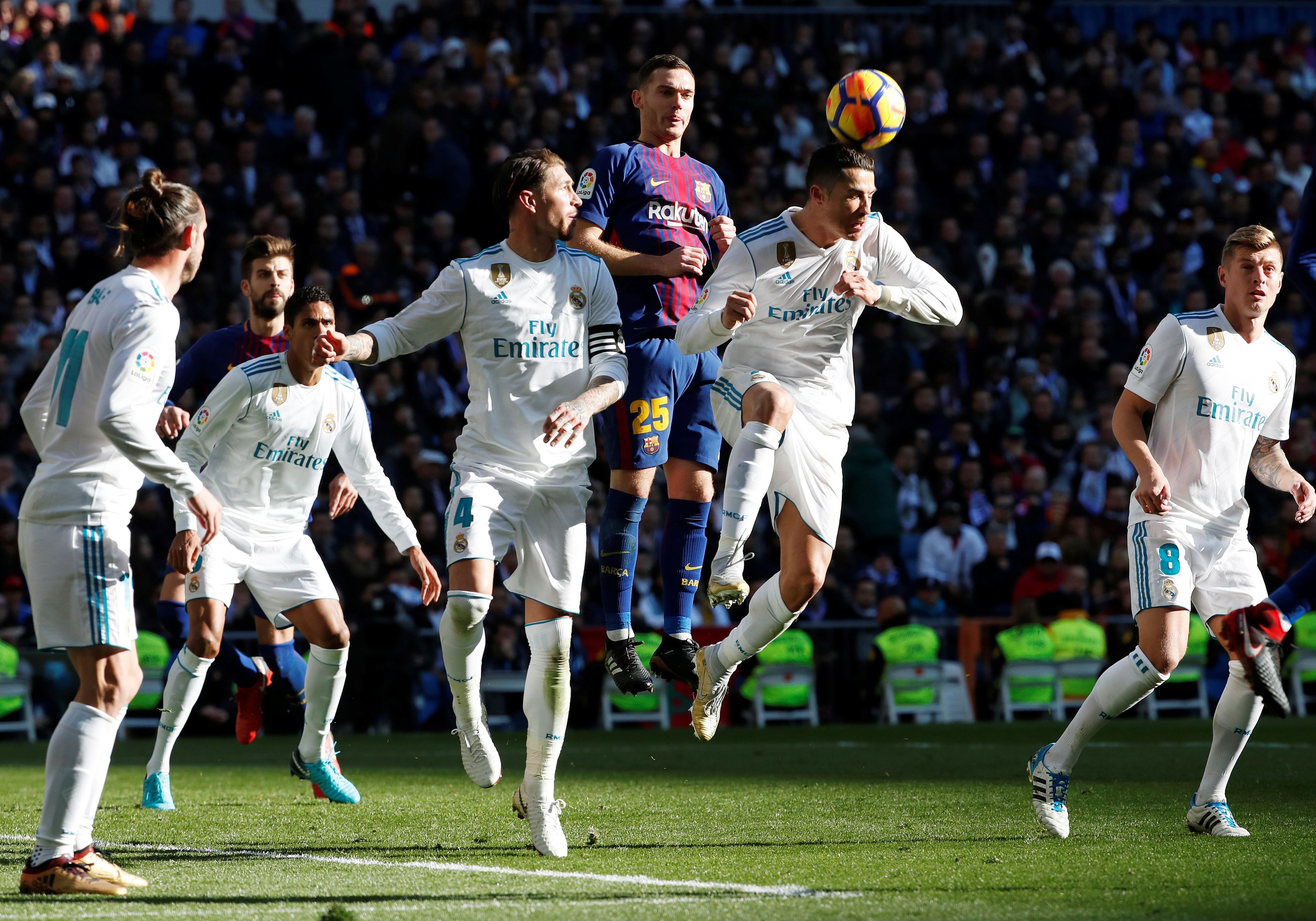 Futbolistas del Real Madrid y del FC Barcelona disputan un balón de cabeza.
