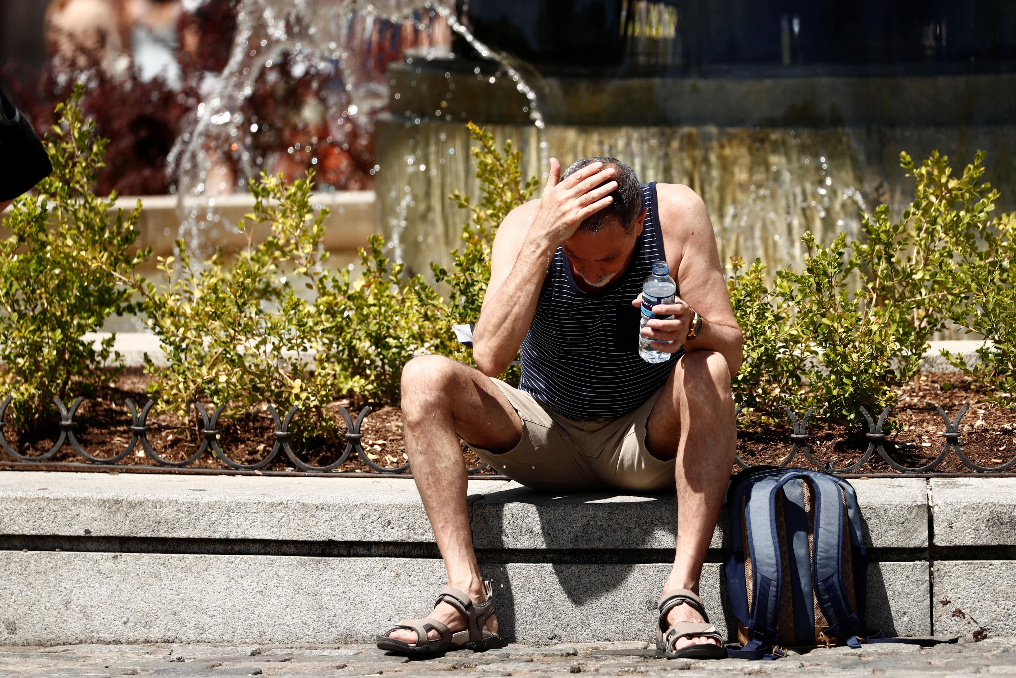 Un hombre se echa agua en la cabeza por el calor, en España.