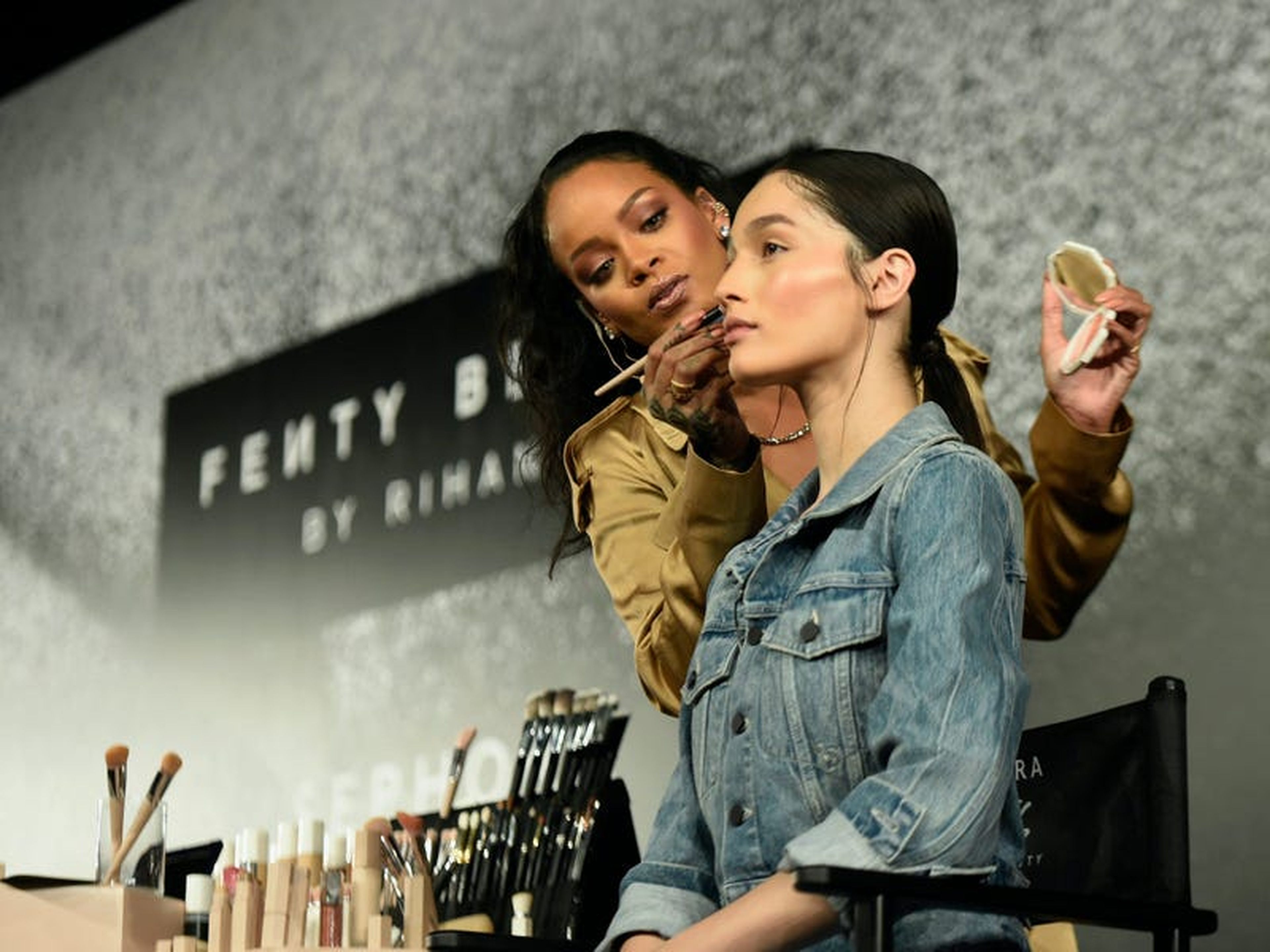 Rihanna aplica los productos Fenty Beauty a una modelo en 201