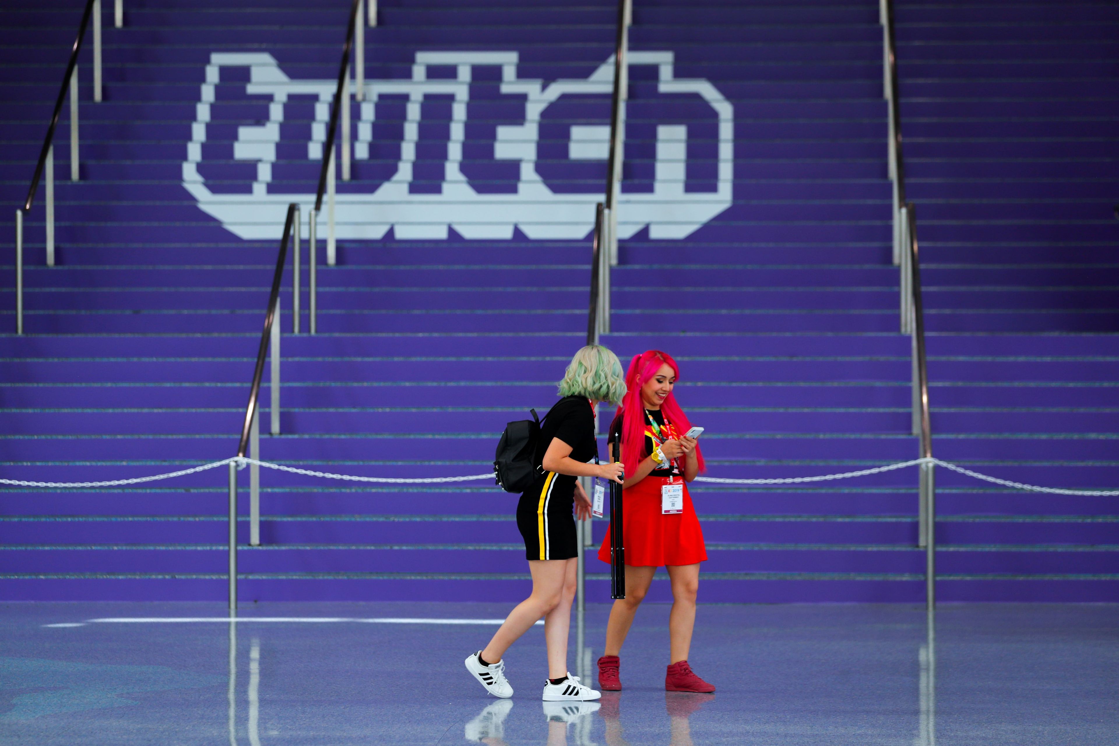 Dos asistentes pasan al lado del logo de Twitch en la feria de videojuegos E3 de Los Ángeles (EEUU).