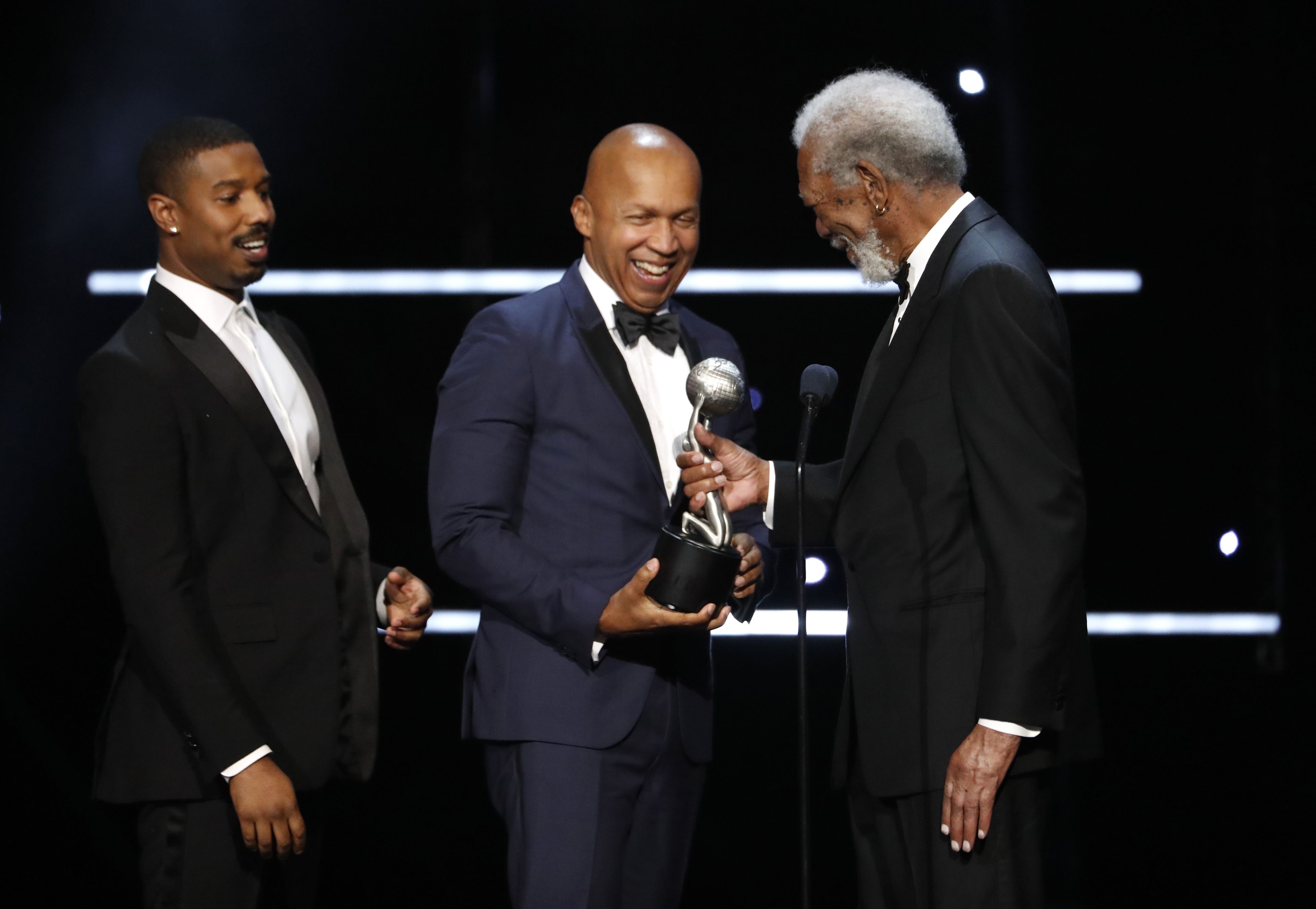 Bryan Stevenson, en el centro, recoge un premio de manos de Morgan Freeman, acompañado por Michael B. Jordan.
