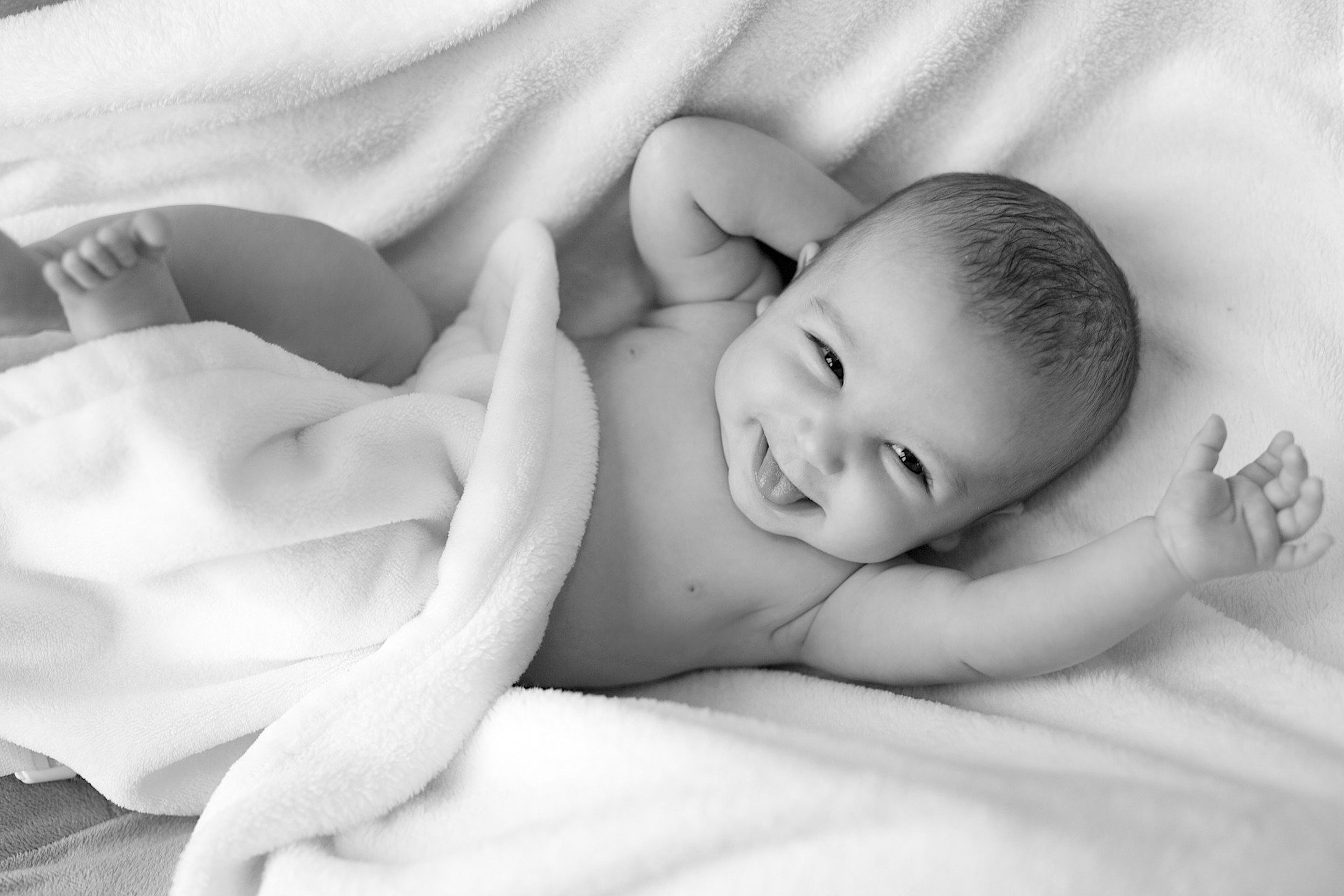 Un bebe sonríe y mueve sus brazos.
