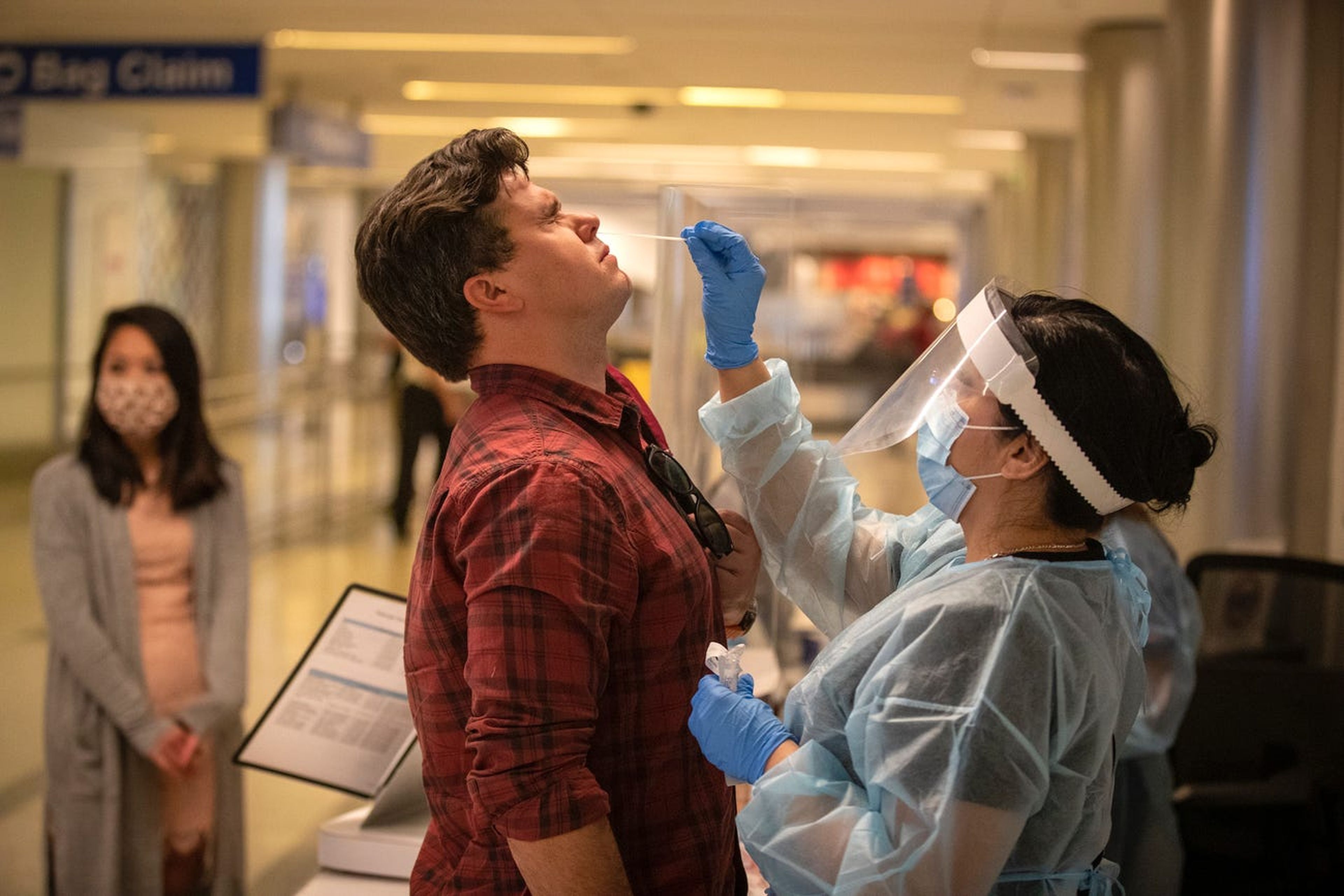 La trabajadora sanitaria Elizabeth Cameros realiza una prueba de COVID-19 al viajero Wade Hopkins en el aeropuerto internacional de Los Ángeles el 23 de noviembre de 2020.