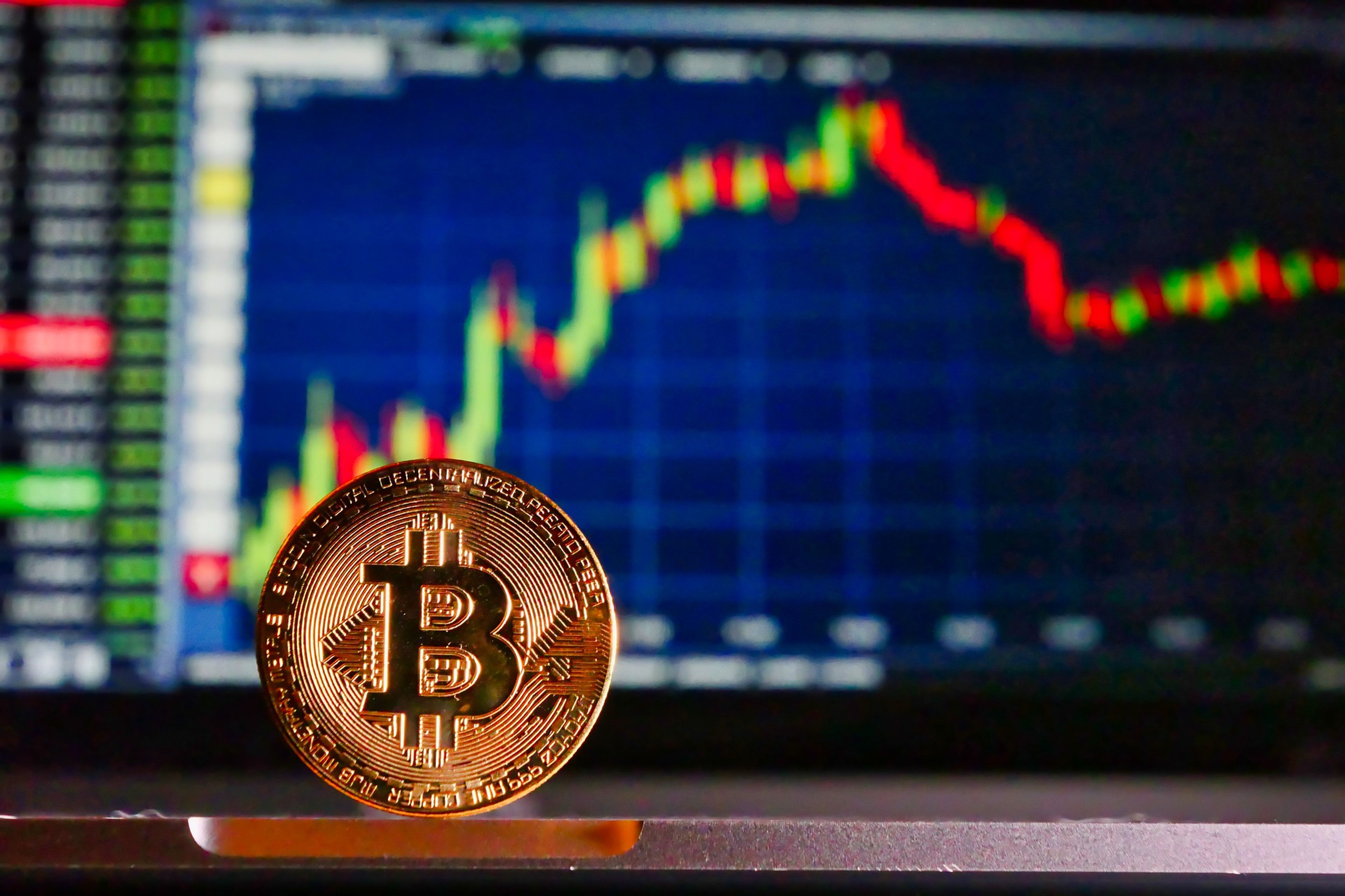 Una moneda de bitcoin delante de un gráfico.