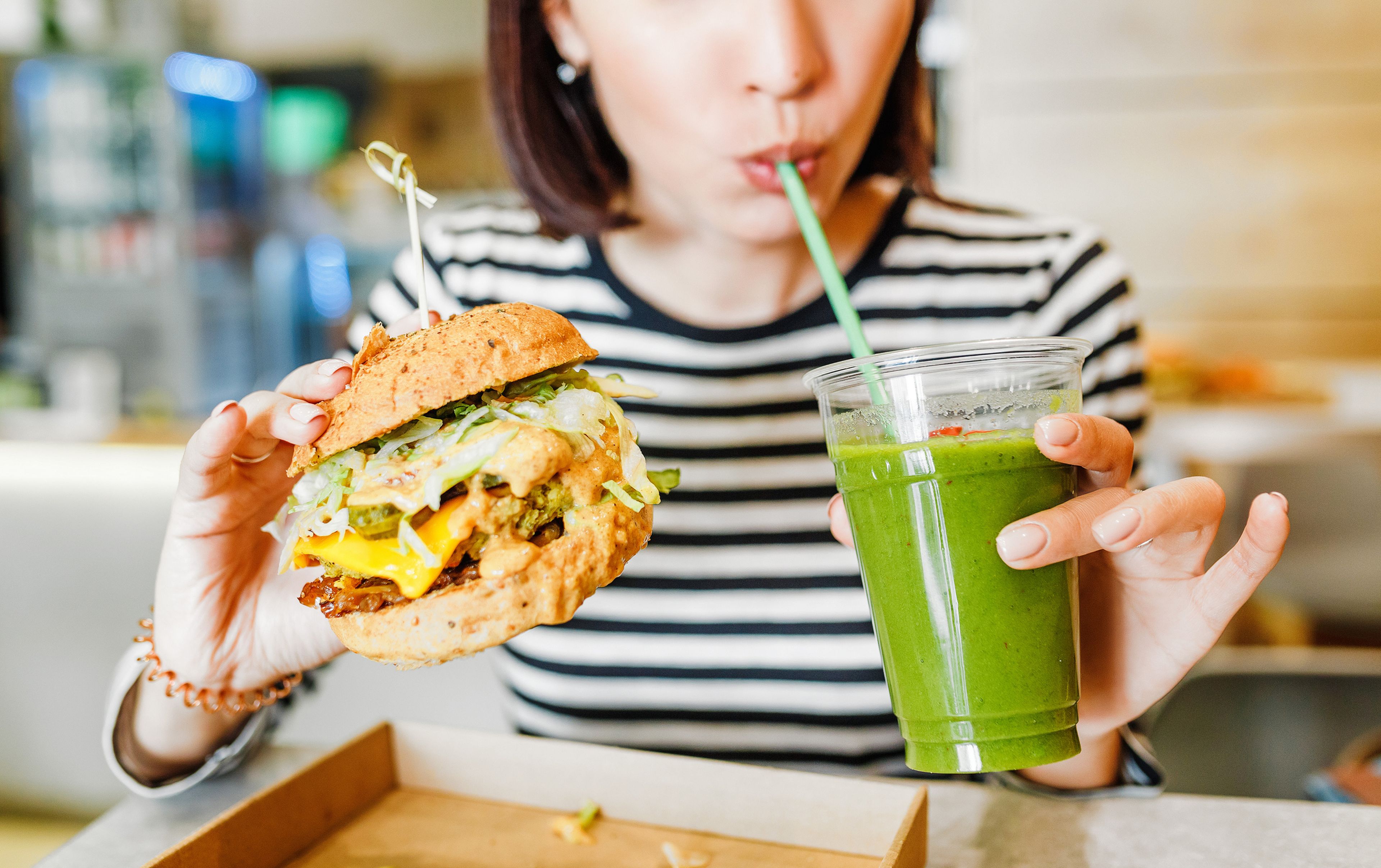 mujer comiendo hamburguesa y batido vegetal