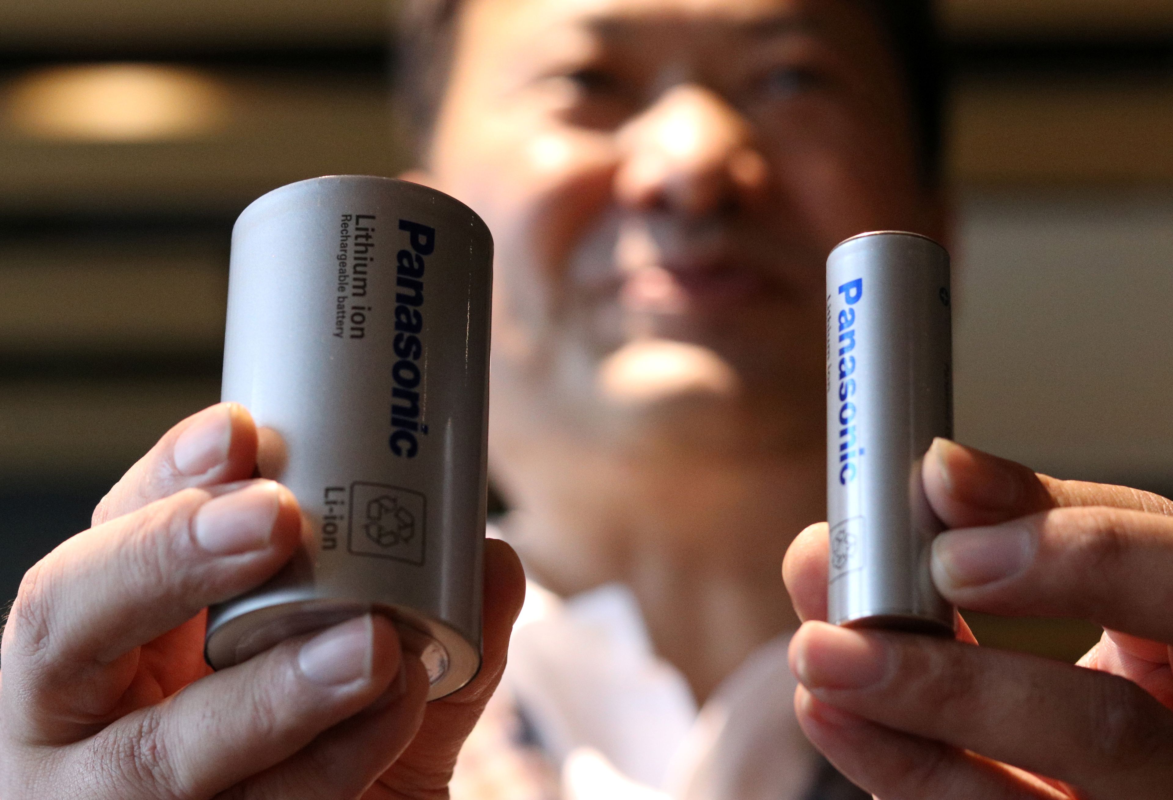 El CEO del área de baterías de Panasonic, Kazuo Tadanobu, muestra el prototipo de la nueva batería 4680 (i) frente a la actual que sirven a Tesla (d).
