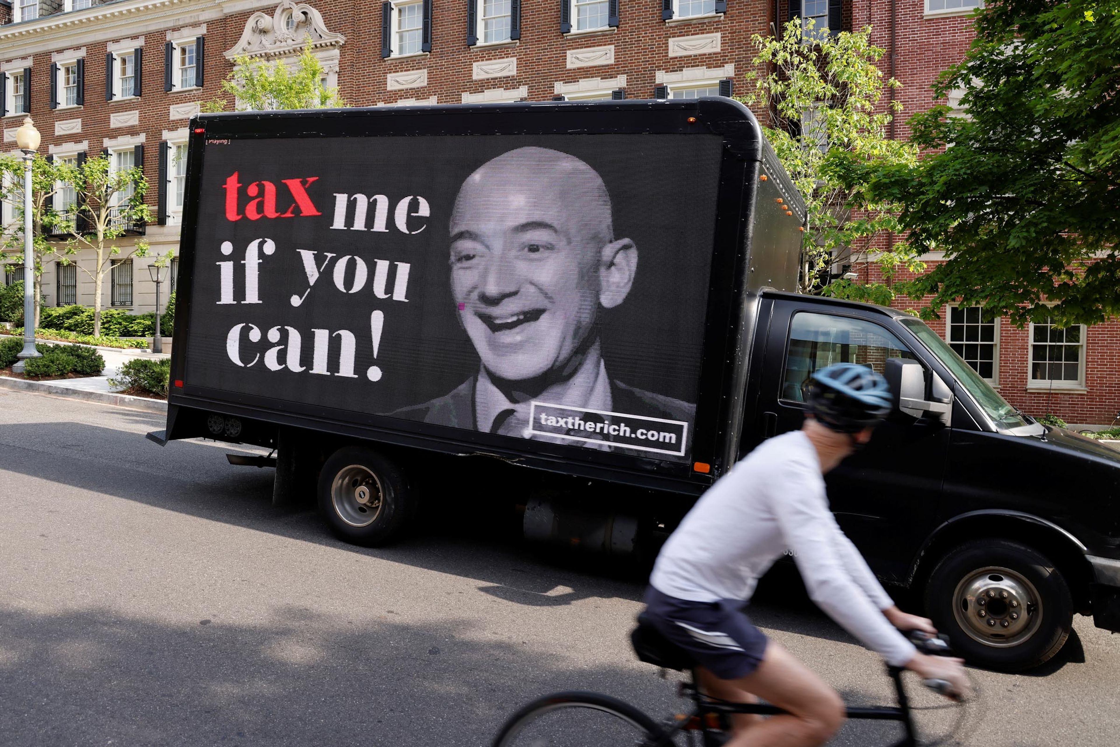 Un camión con un cartel que pide más impuestos para los ricos, con una imagen de Jeff Bezos, pasa por delante de una mansión del fundador de Amazon, en Washington (EE. UU.).