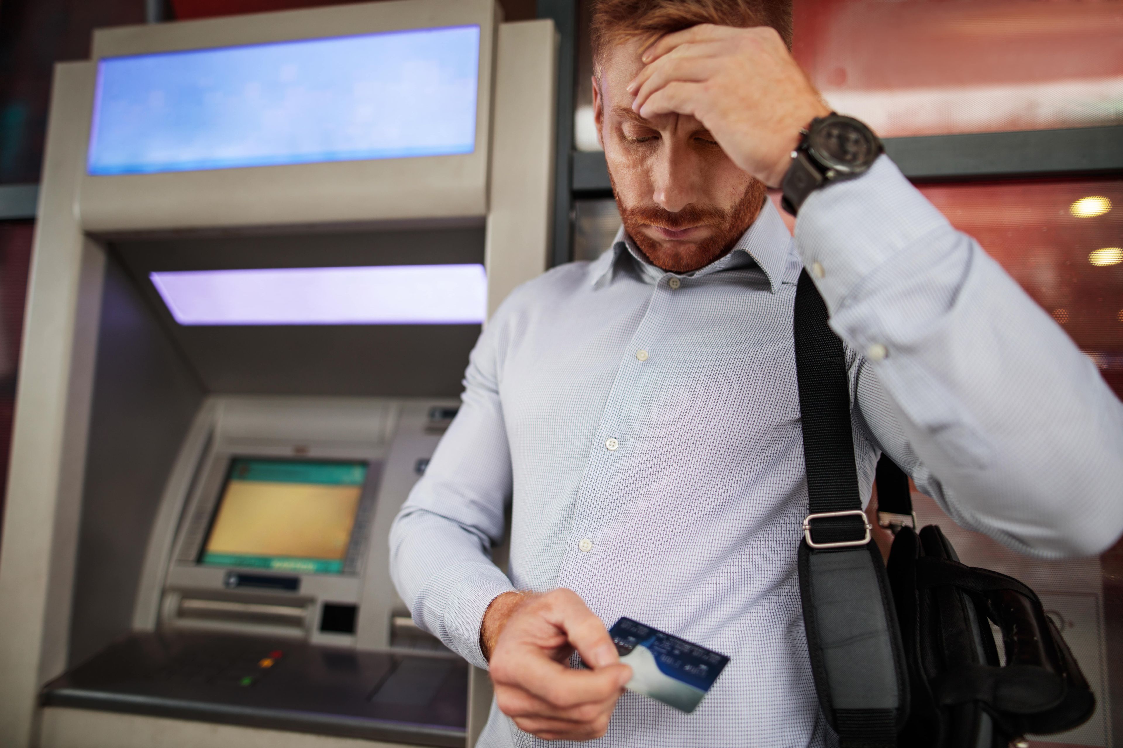 Un hombre mira con preocupación su tarjeta bancaria