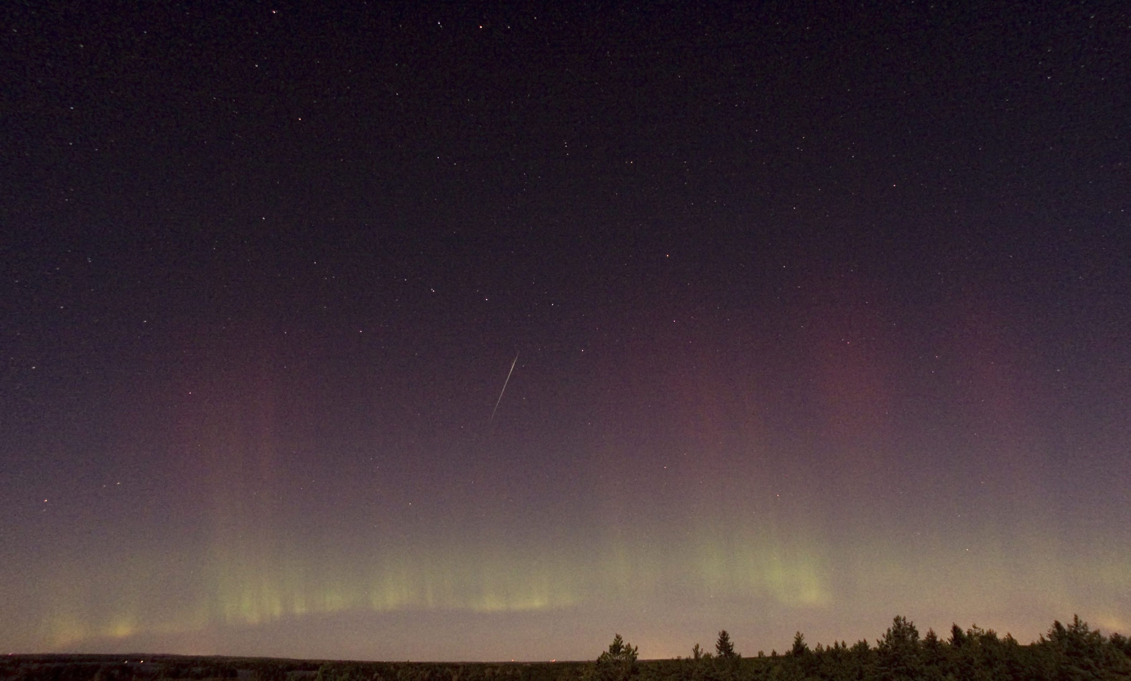 Vista de una estrella fugaz (Dracónida) y una aurora boreal en Suecia, 2011.