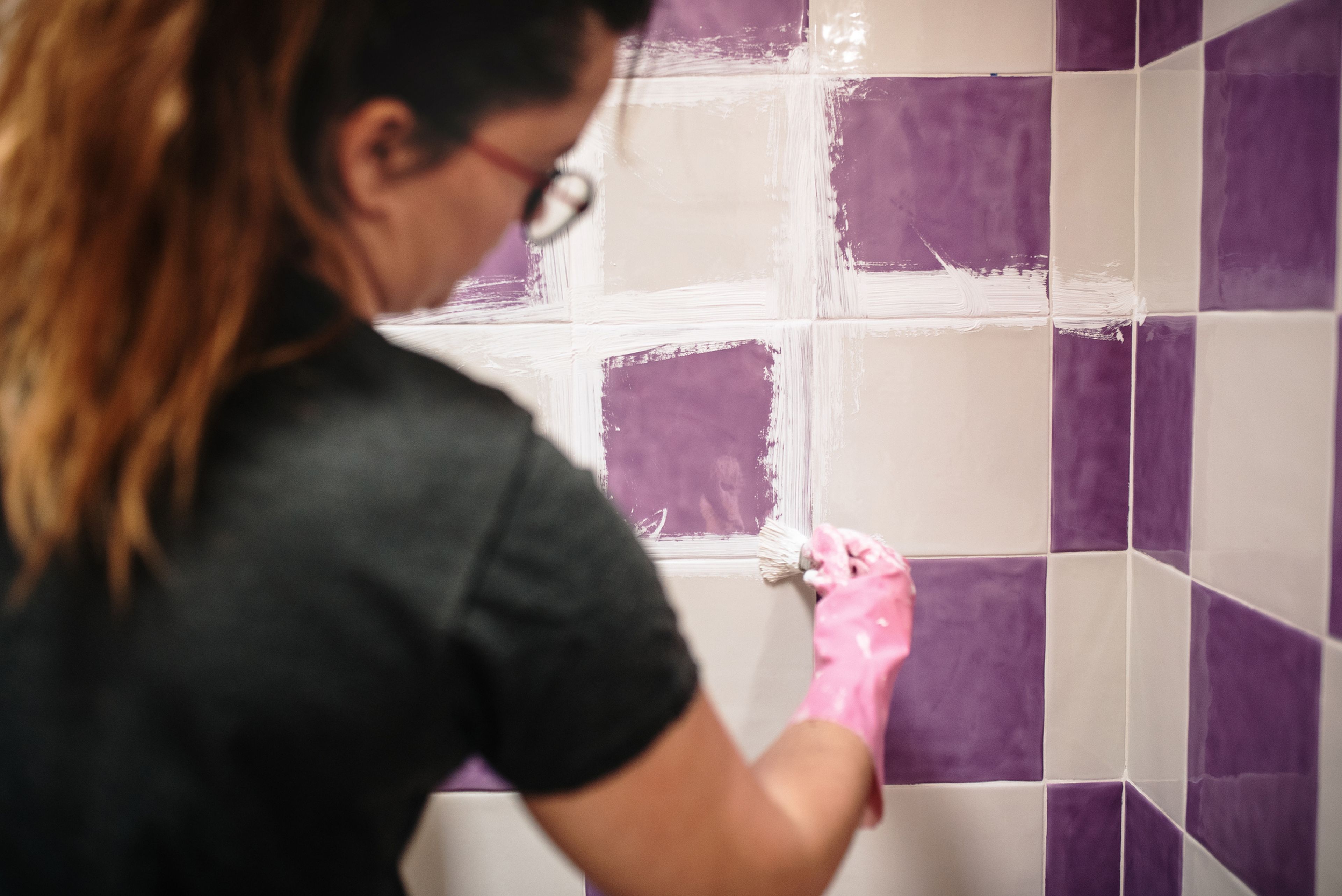 Una mujer arregla los azulejos de casa.