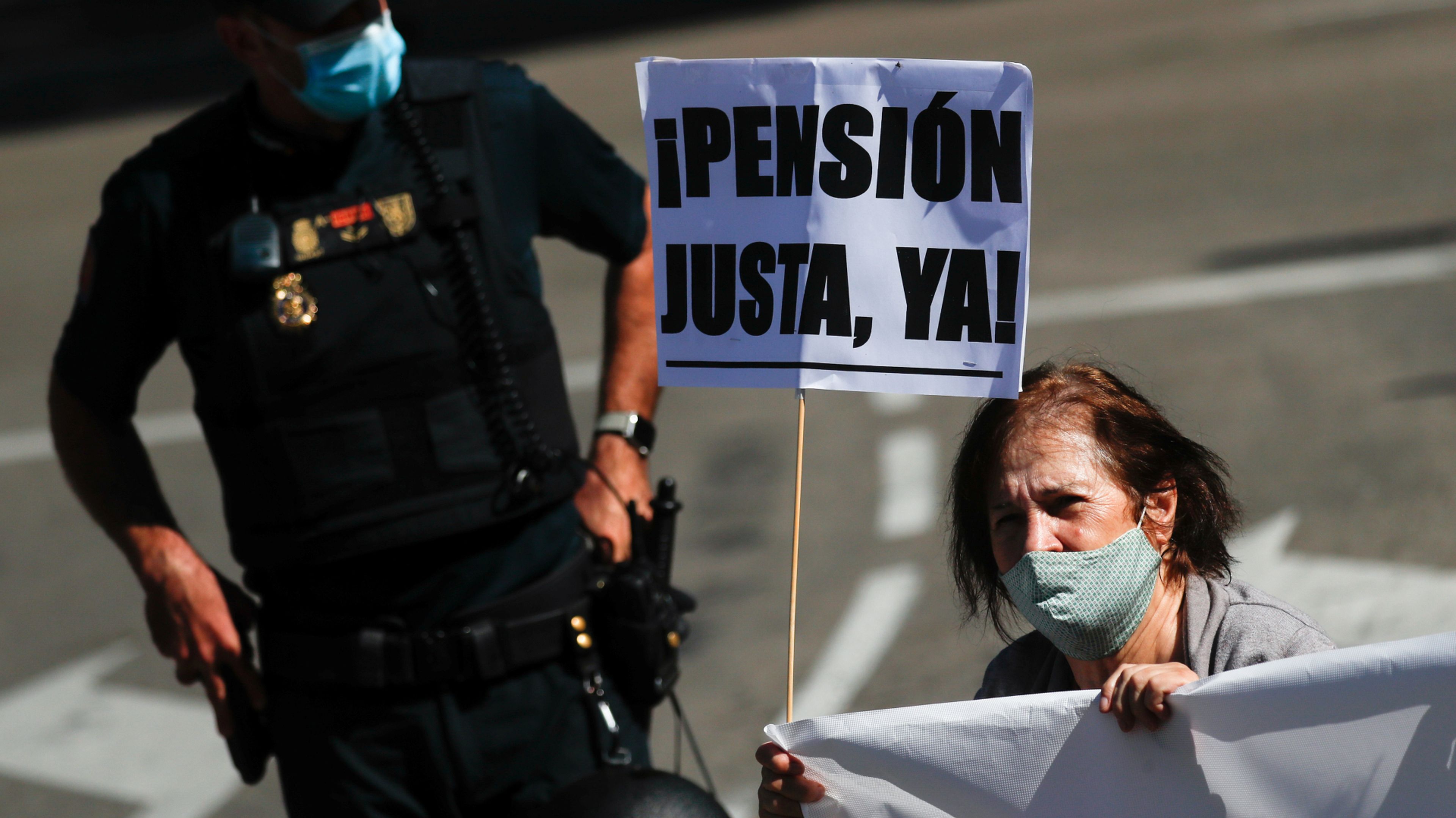 Una mujer con un cartel y una pancarta participa en una manifestación para la mejora del sistema público de pensiones en Madrid