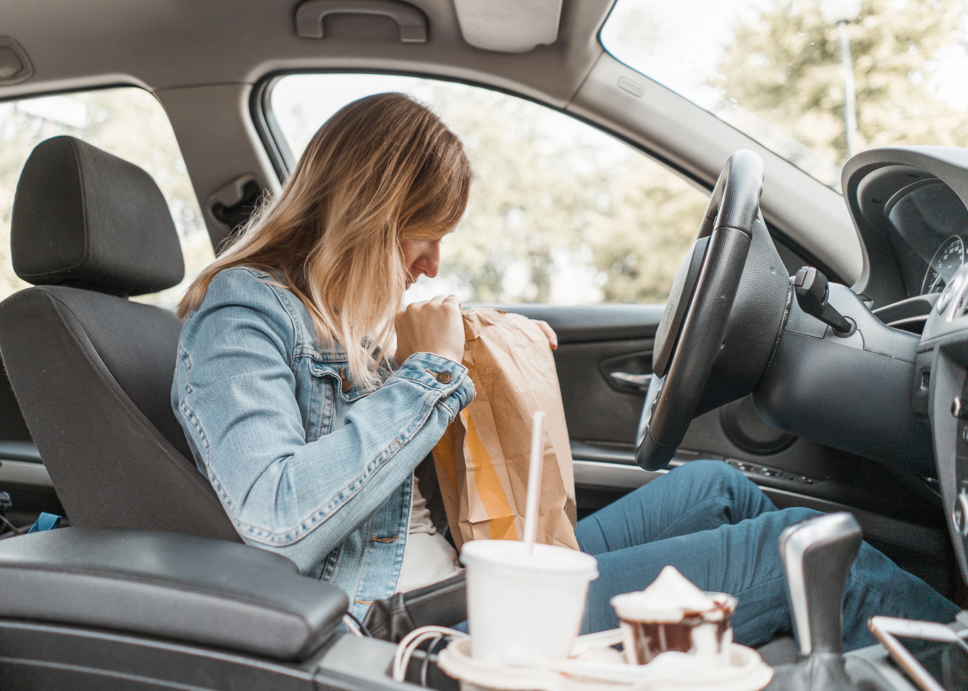 mujer comiendo comida basura en el coche