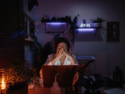 Una mujer exhausta delante del ordenador mientras trabaja.