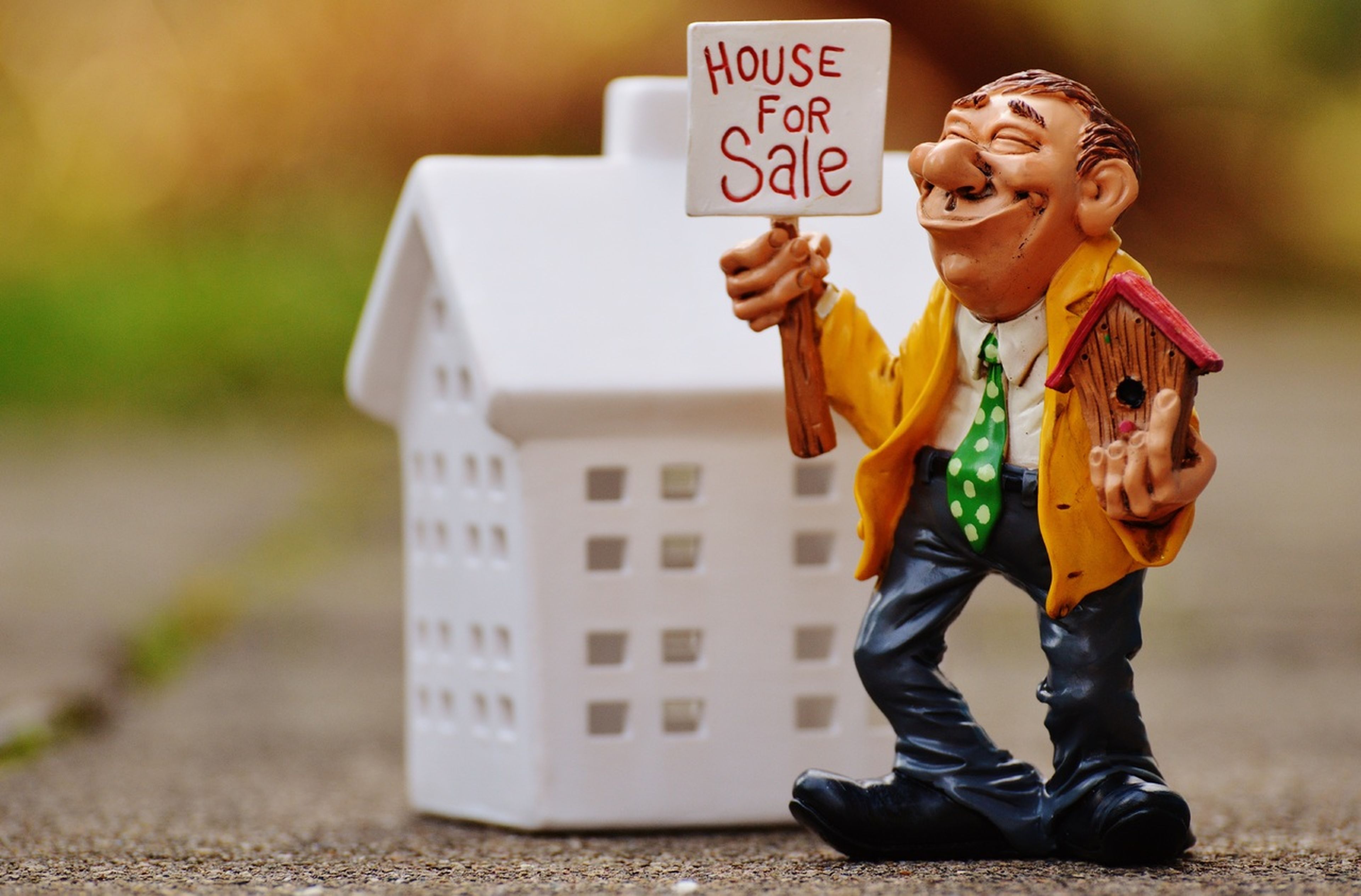 Un muñeco con un cartel en el que se anuncia la venta de una casa.