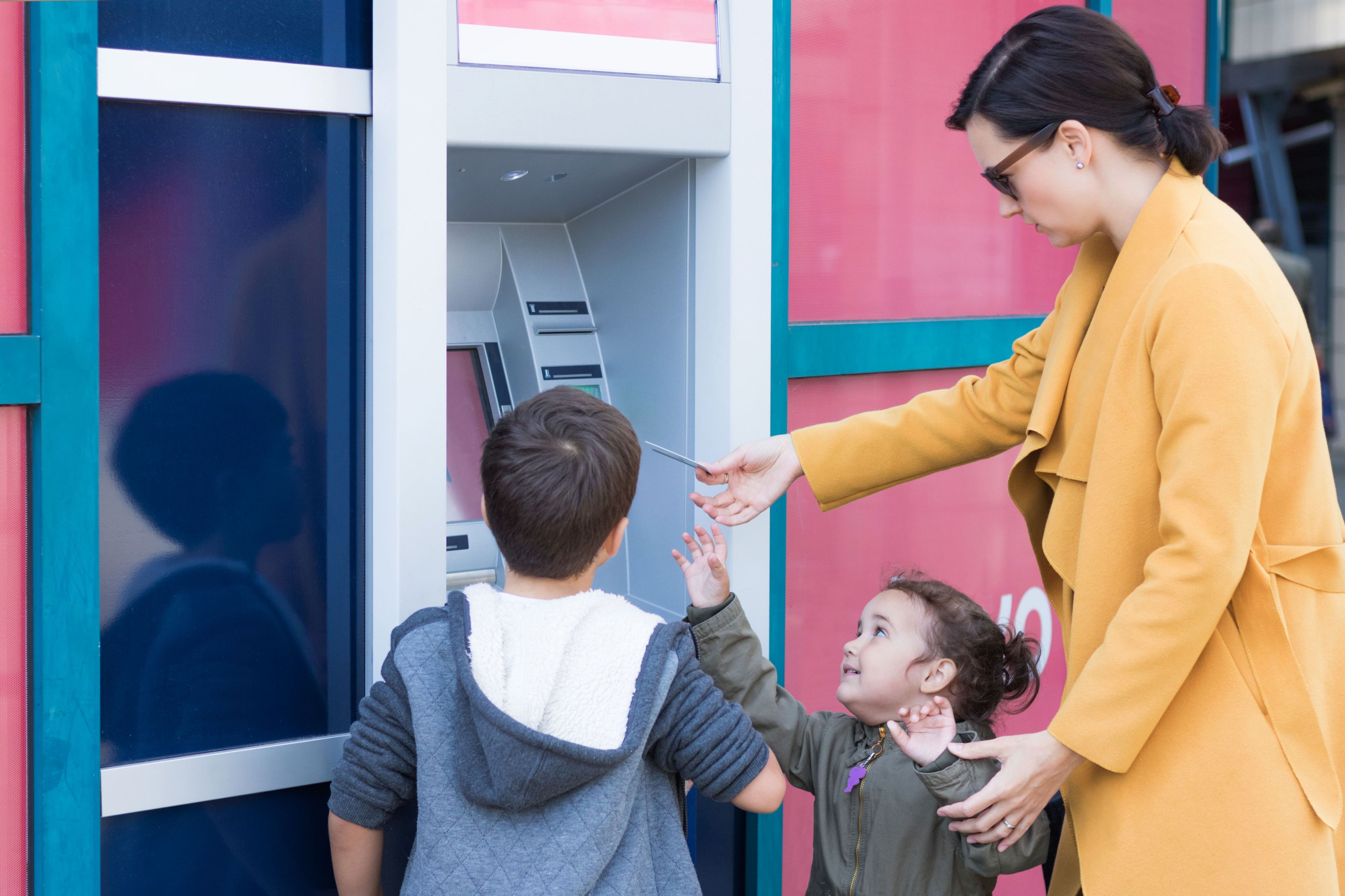 Niños sacando dinero de un cajero automático