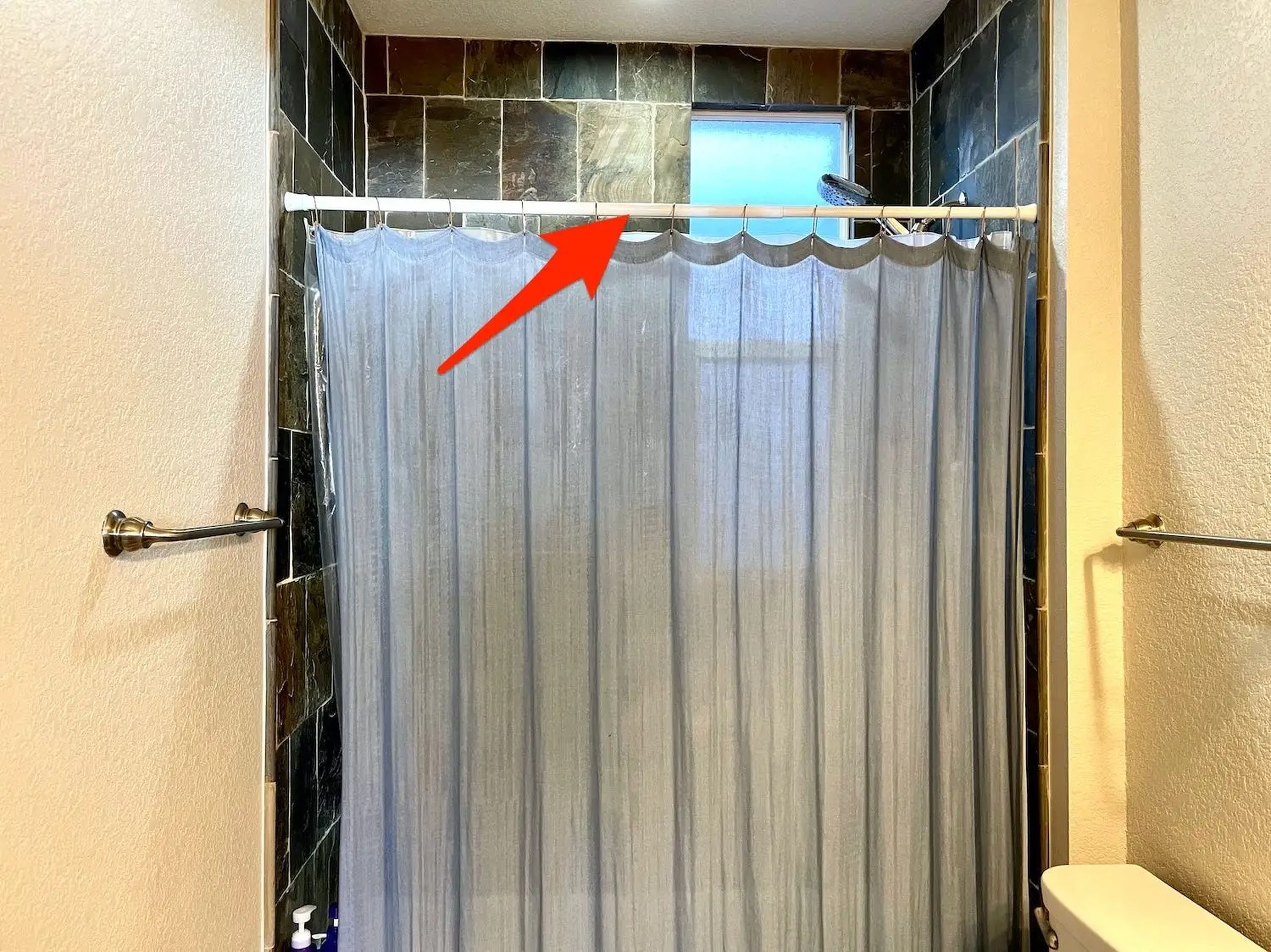 La flecha apunta a la barra de cortina de la ducha.