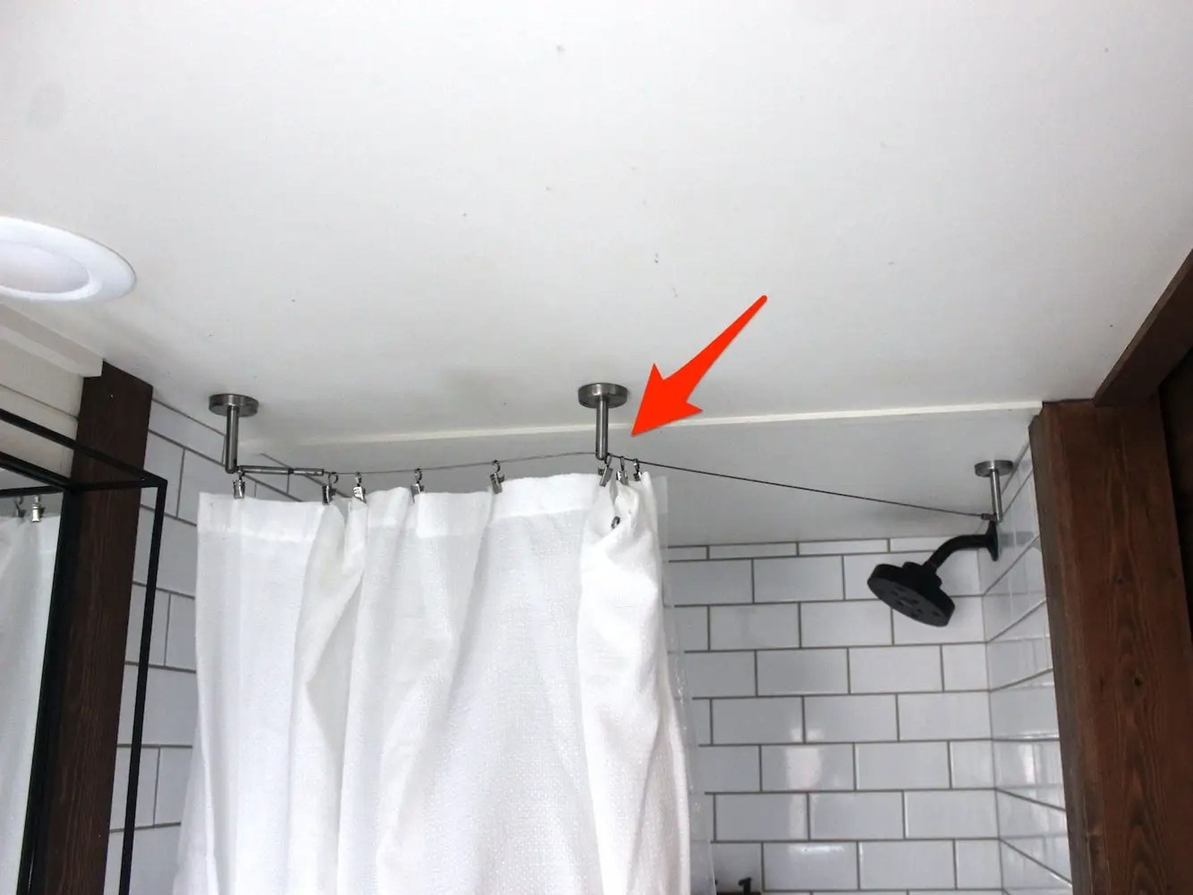 La flecha apunta a un cable que sirve como barra de ducha de la pequeña vivienda de WeeCasa.