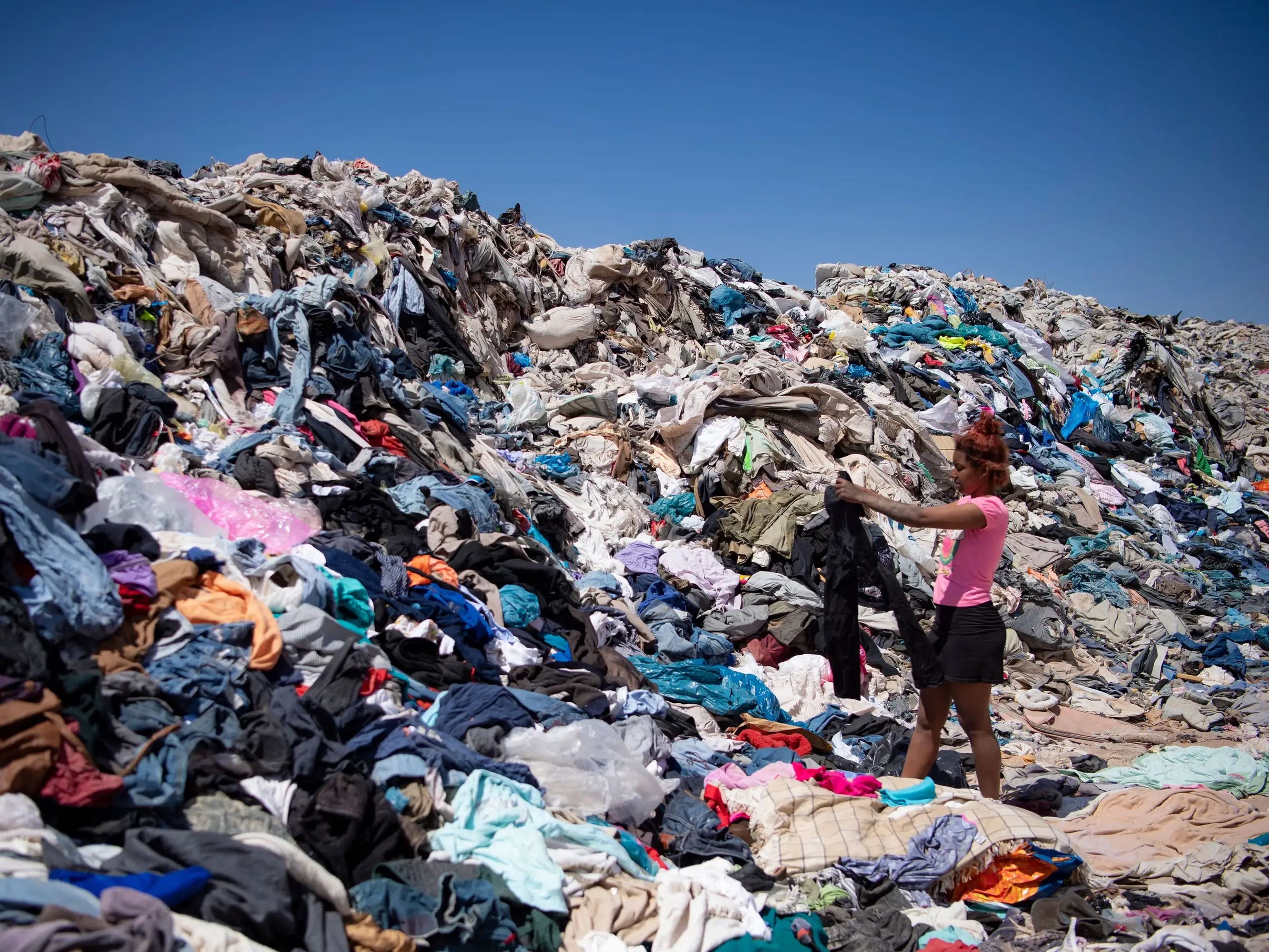 Una mujer busca ropa usada entre toneladas de prendas abandonadas en el desierto de Atacama, en Alto Hospicio, Iquique, Chile.