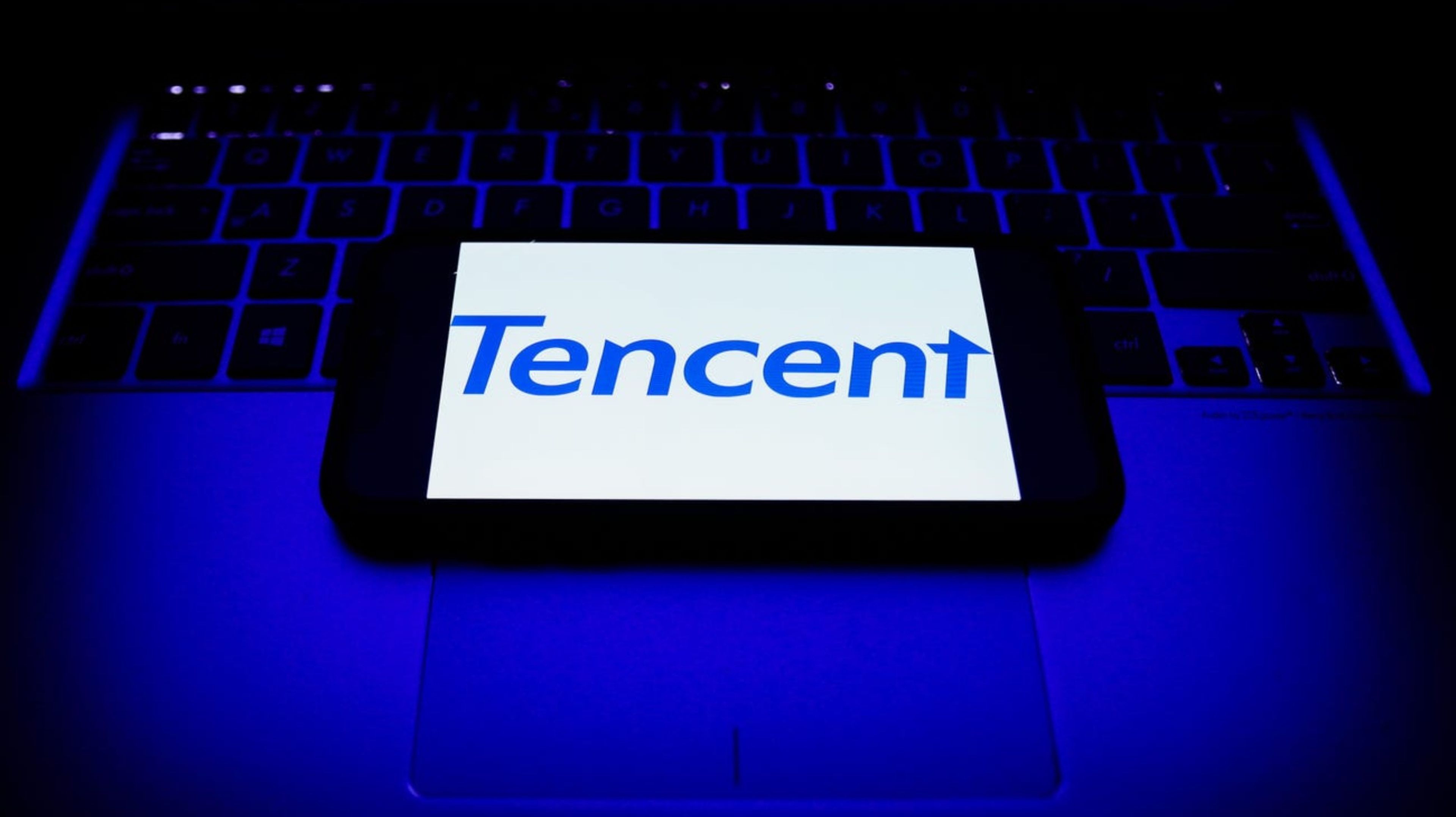 El logotipo de Tencent mostrado en la pantalla de un teléfono y sobre un teclado de un ordenador.