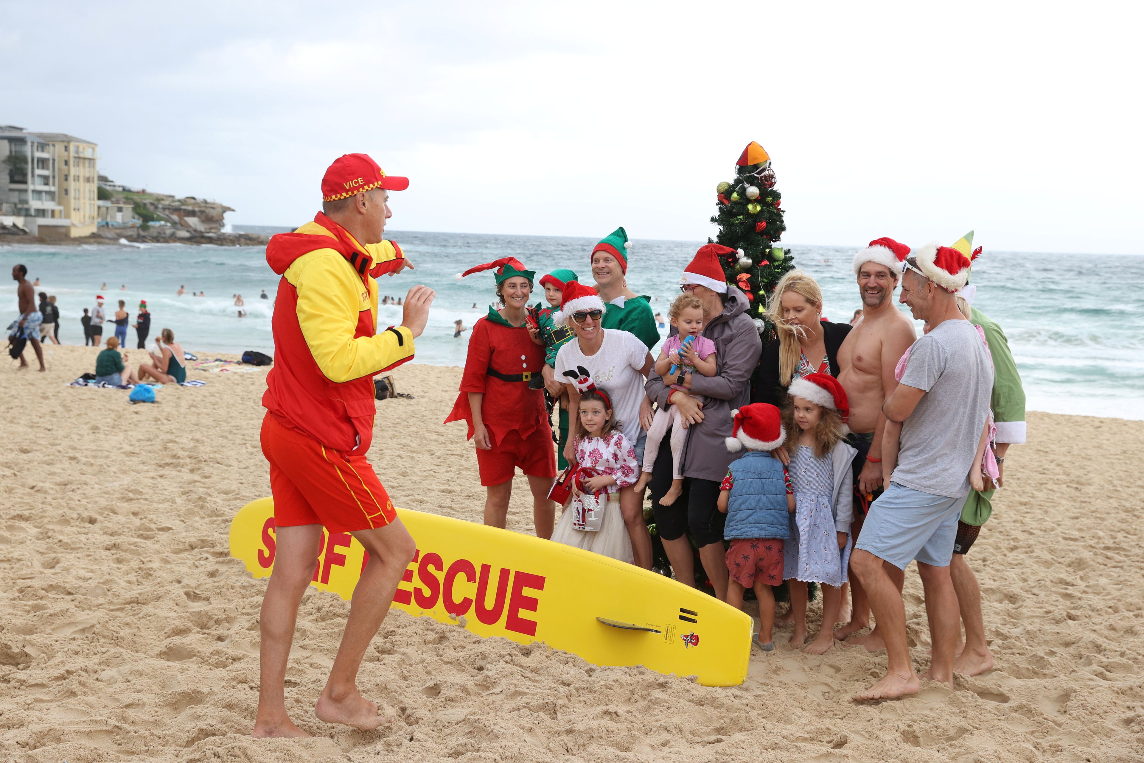 Un grupo de personas con trajes navideños posan para una foto junto al árbol de Navidad en la playa de Bondi en Sídney, Australia, el 25 de diciembre de 2020.