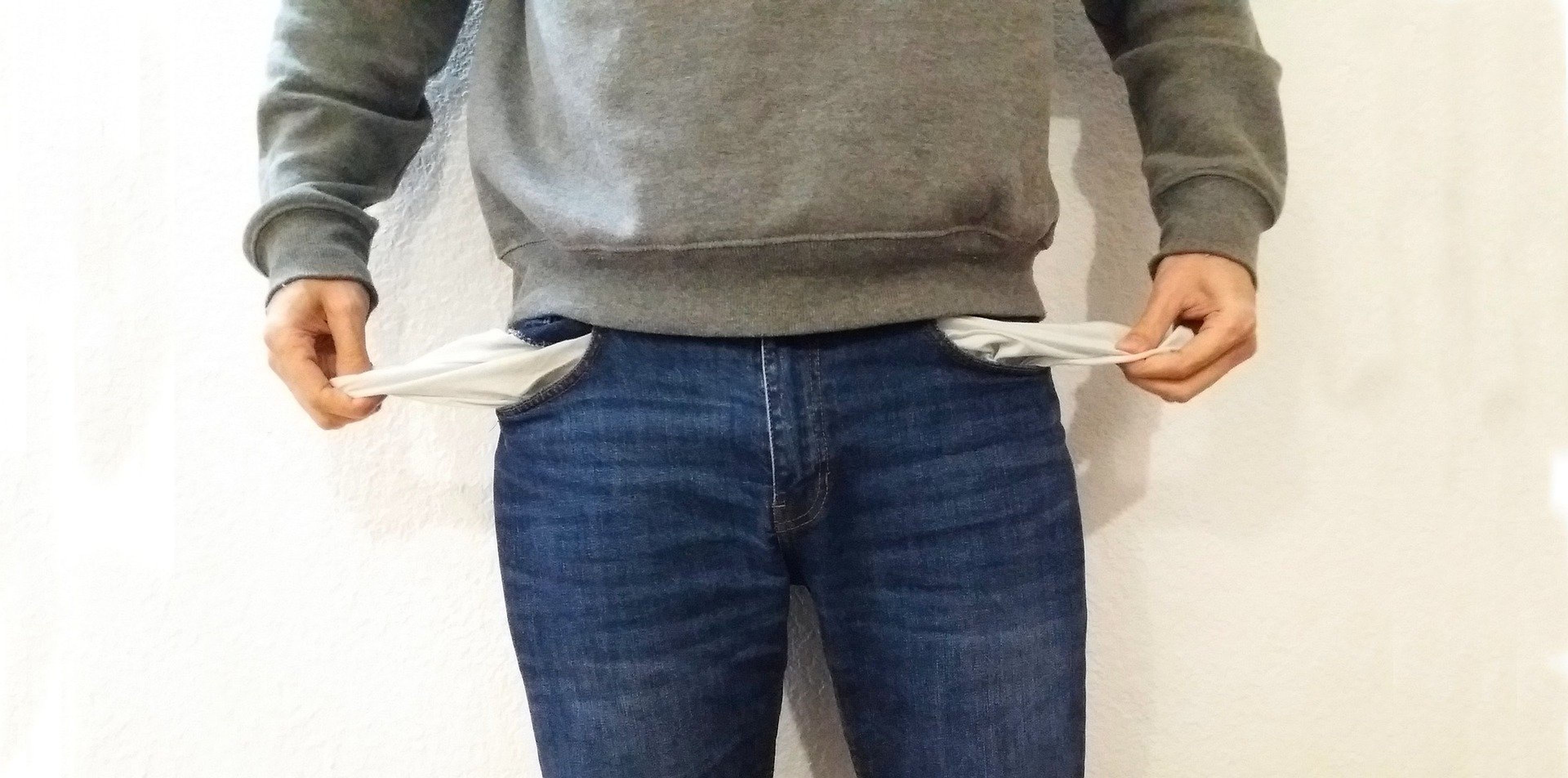 Una persona muestra sus bolsillos vacíos.