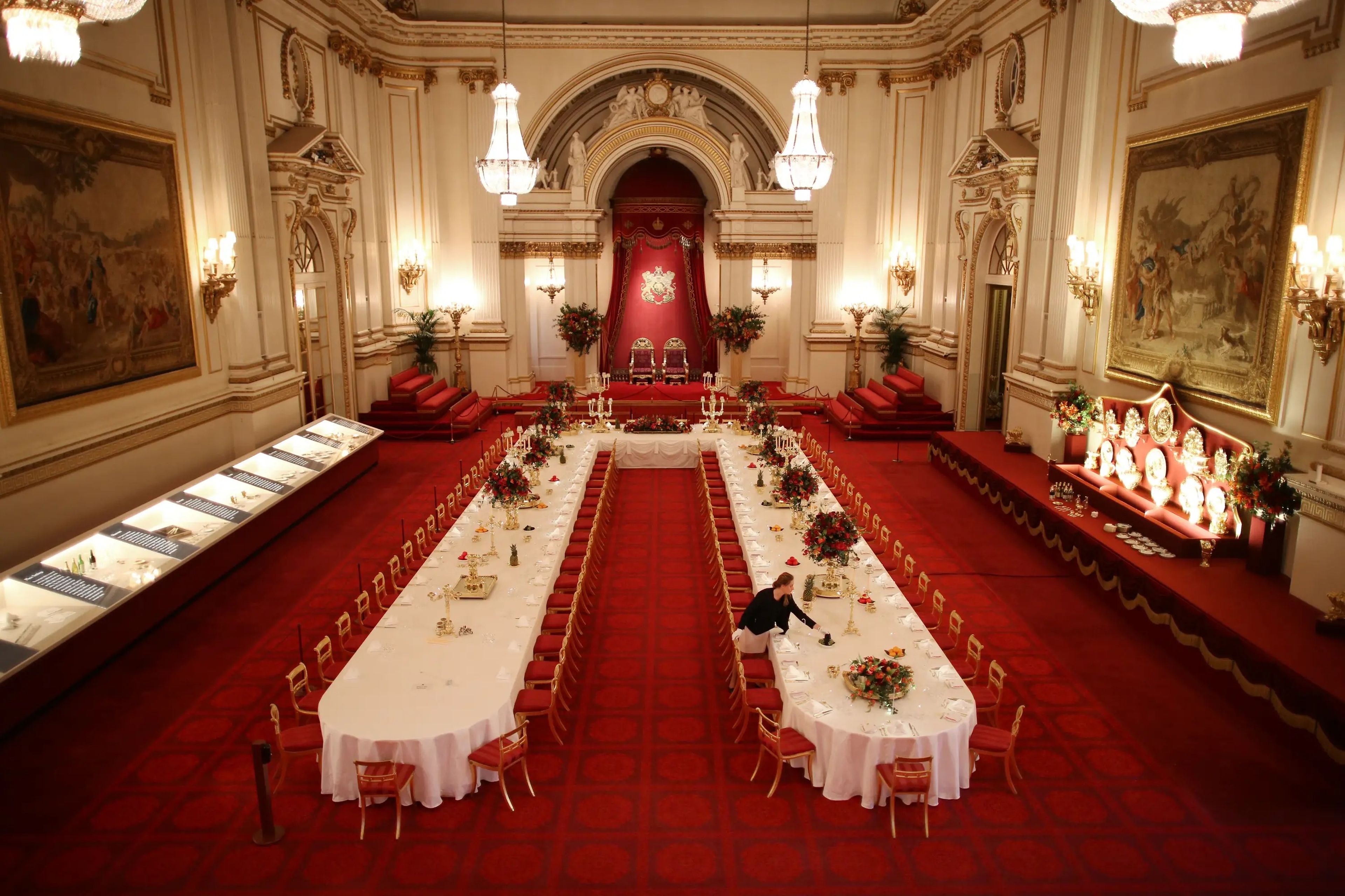 Un miembro del personal es el encargado de montar las mesas en el salón de baile del palacio de Buckingham.