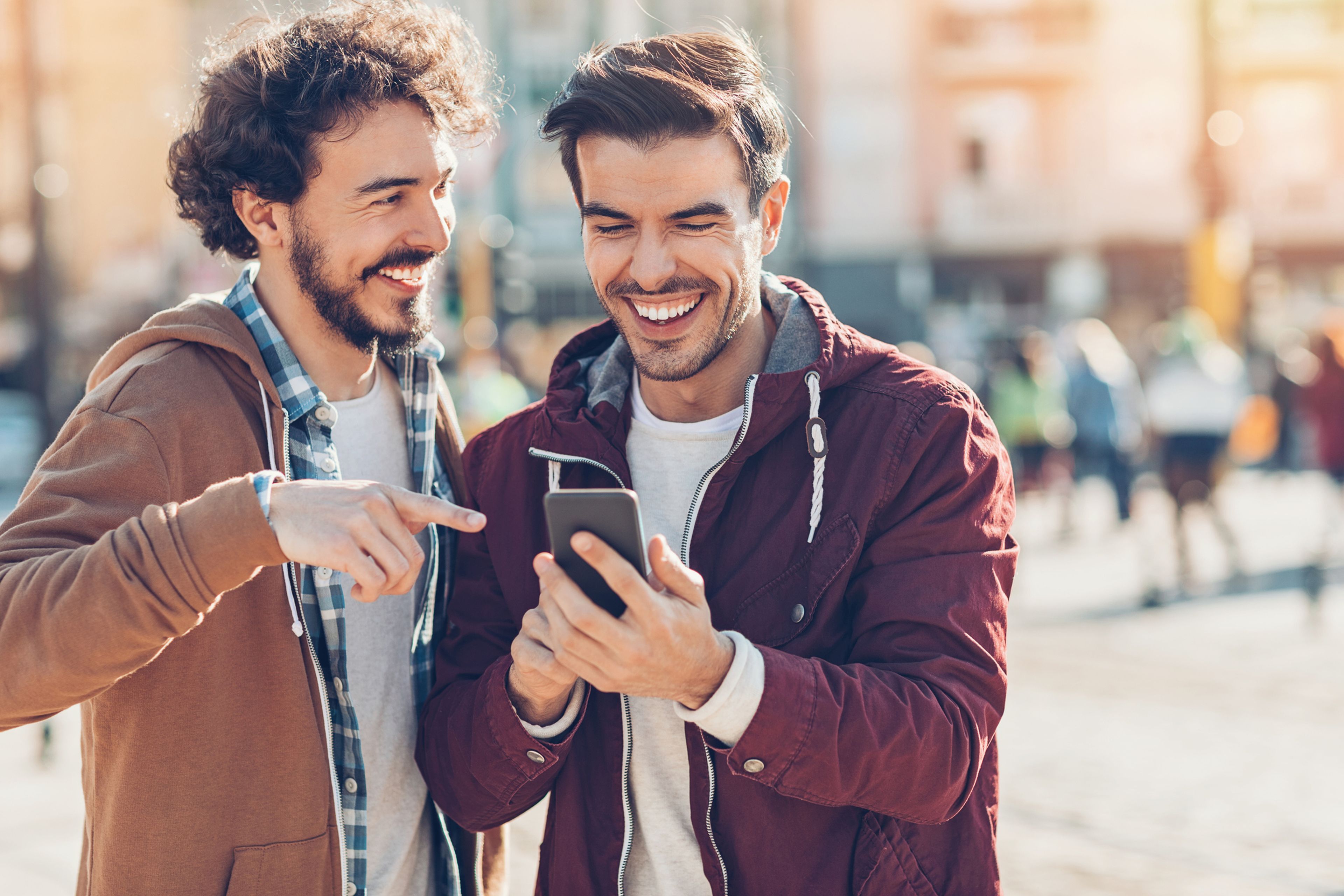 2 hombres riendo mirando un móvil