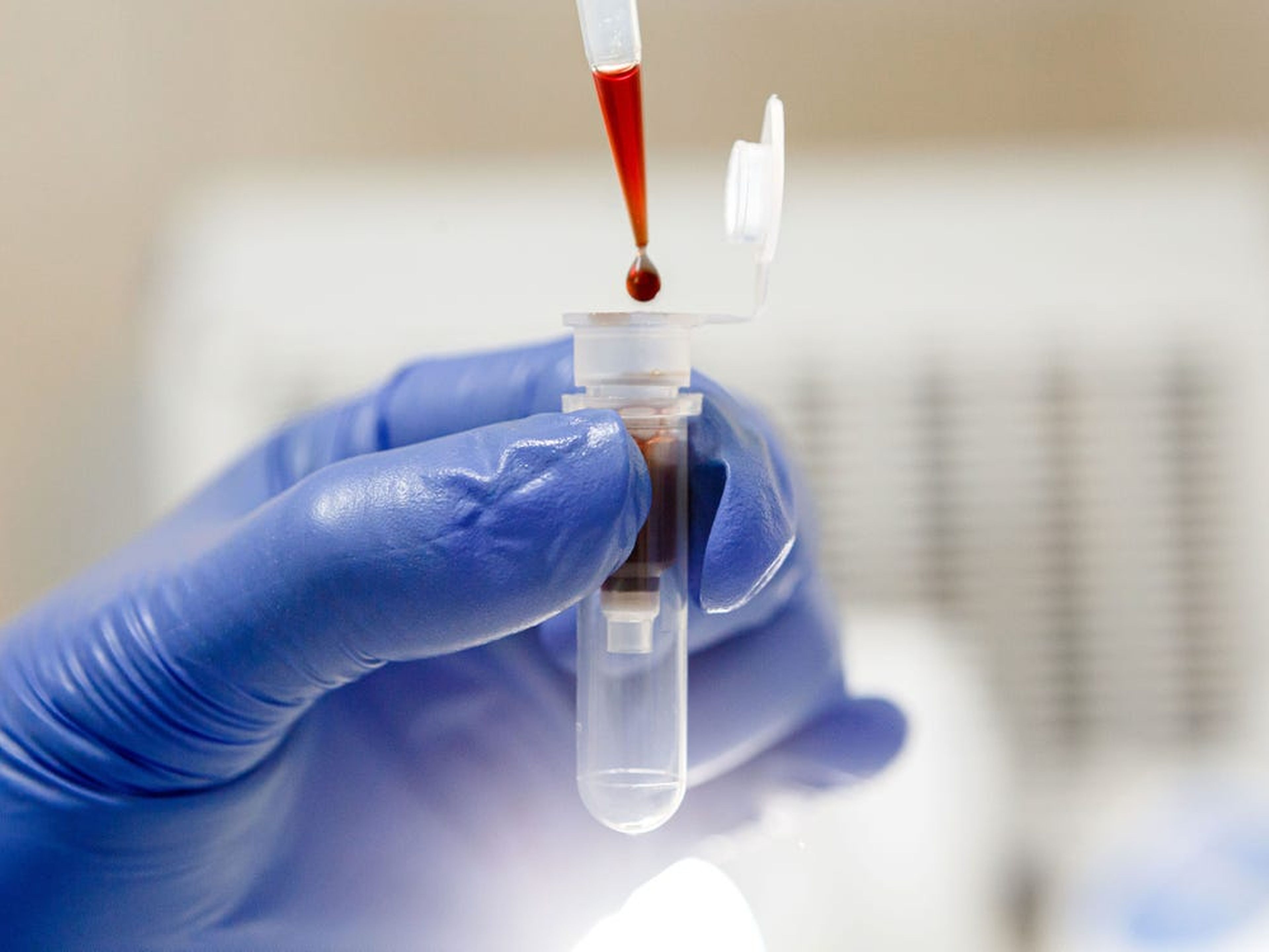 Un científico gotea sangre en un tubo de ensayo.