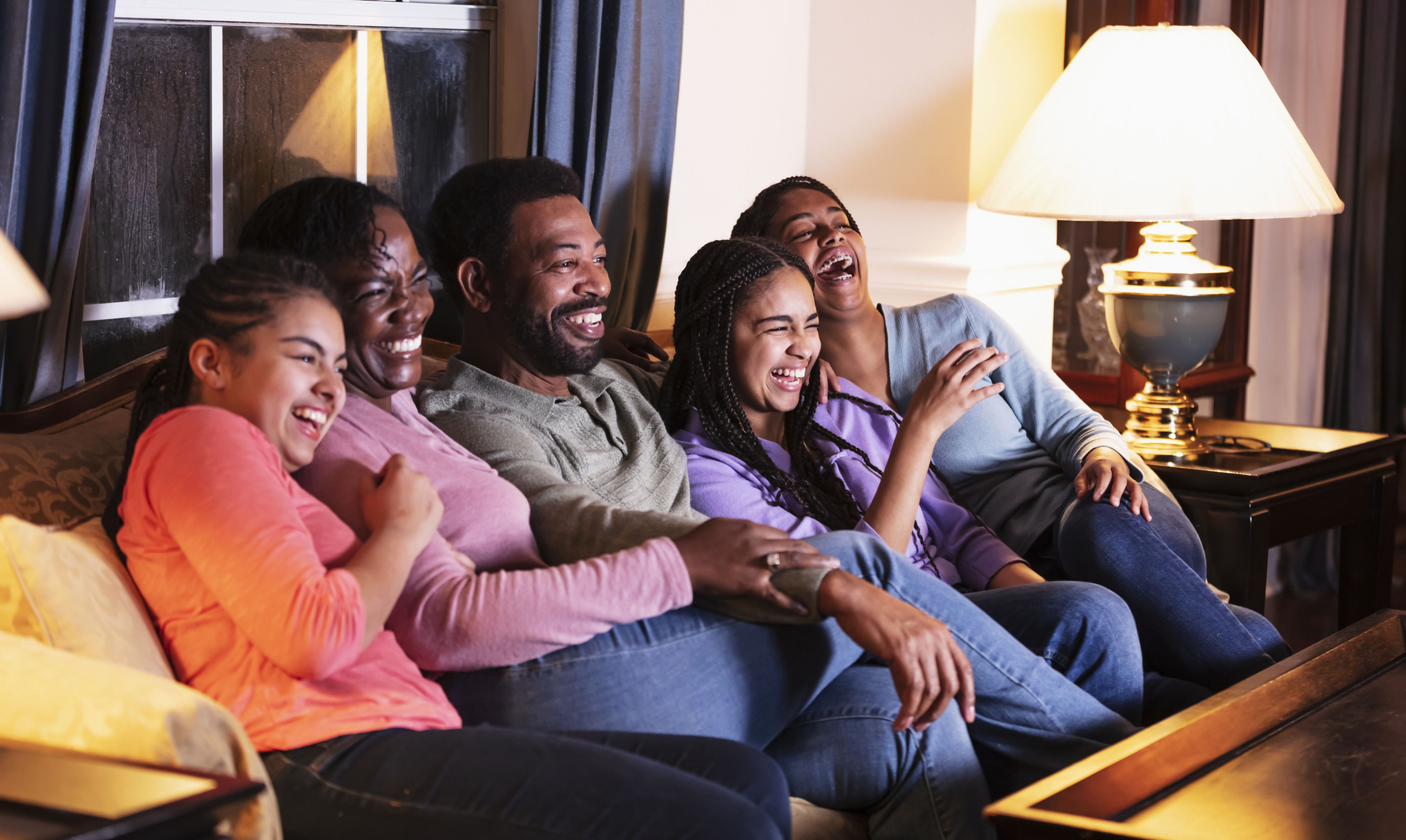 Una familia sonríe viendo la televisión.