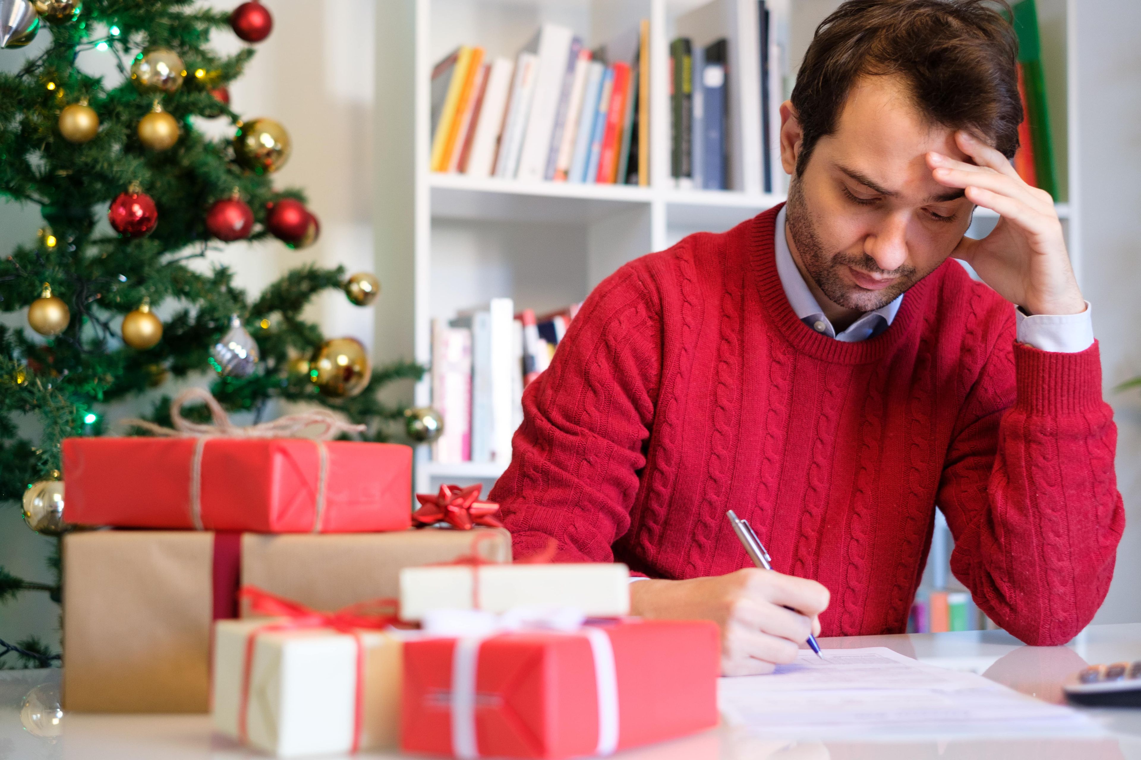 Hombre con regalos de Navidad rellenando papeles