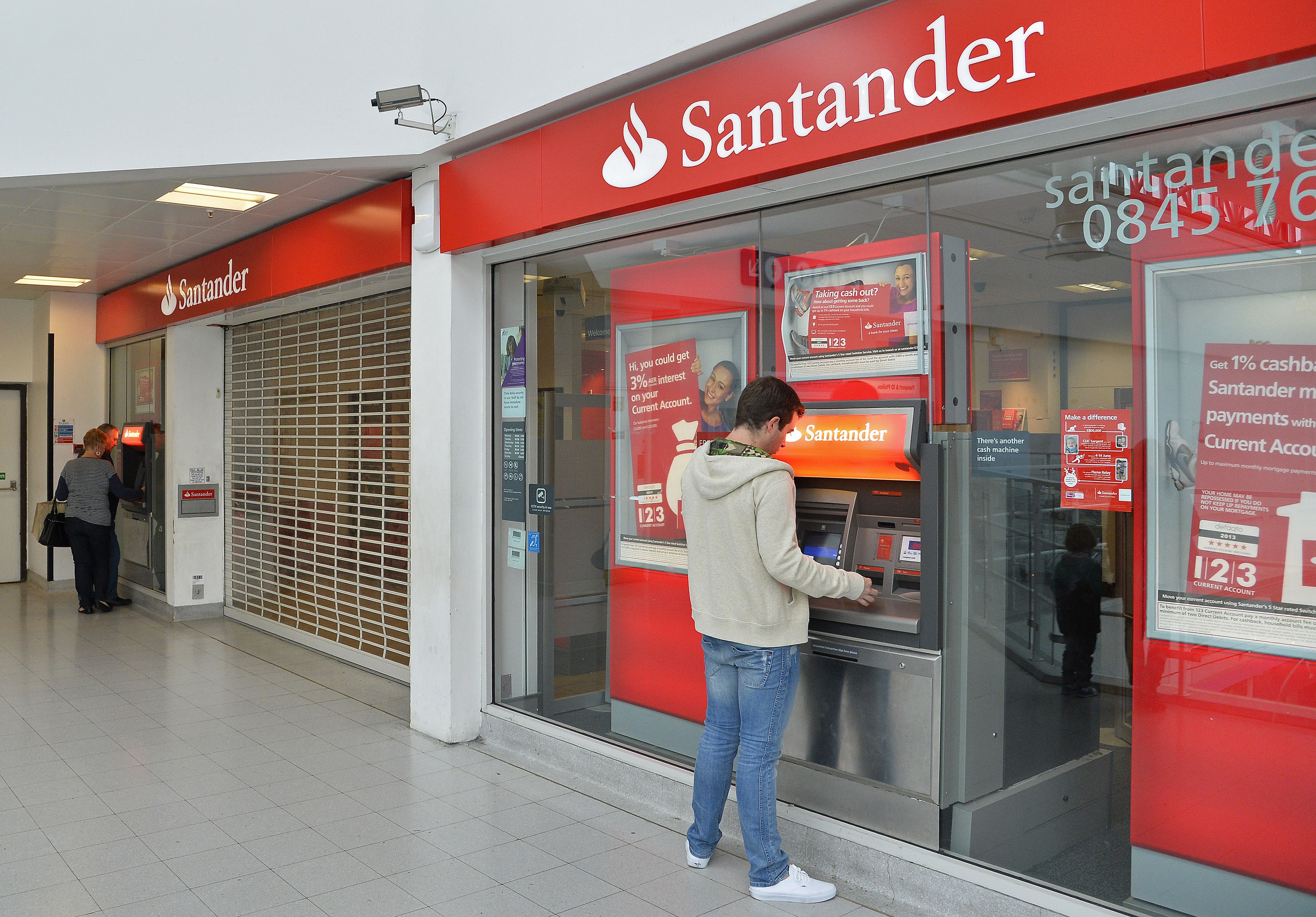 Un hombre saca dinero de un cajero de Banco Santander
