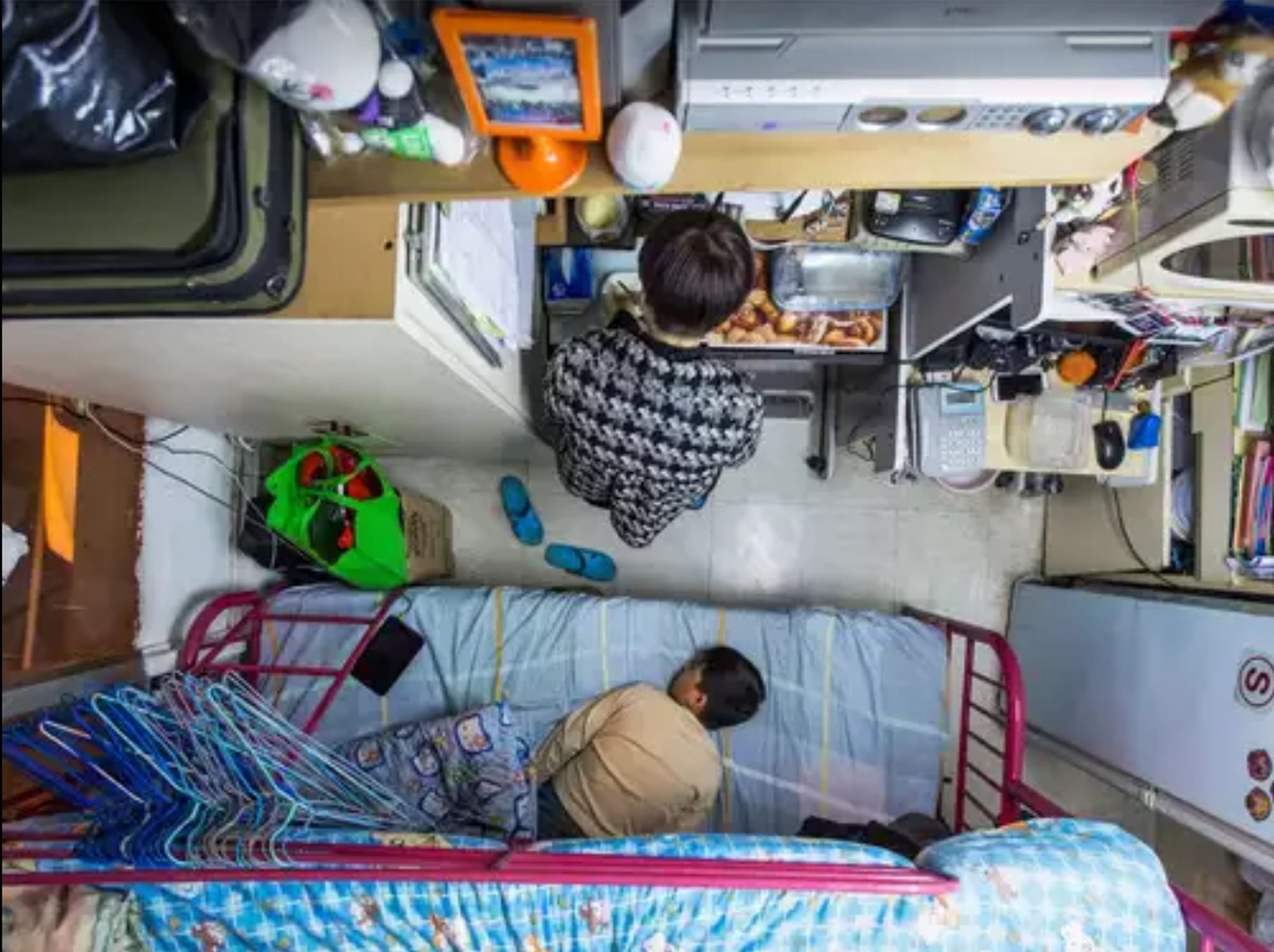 Una madre prepara la comida mientras su hijo duerme en su apartamento de 5 metros cuadrados en Hong Kong.