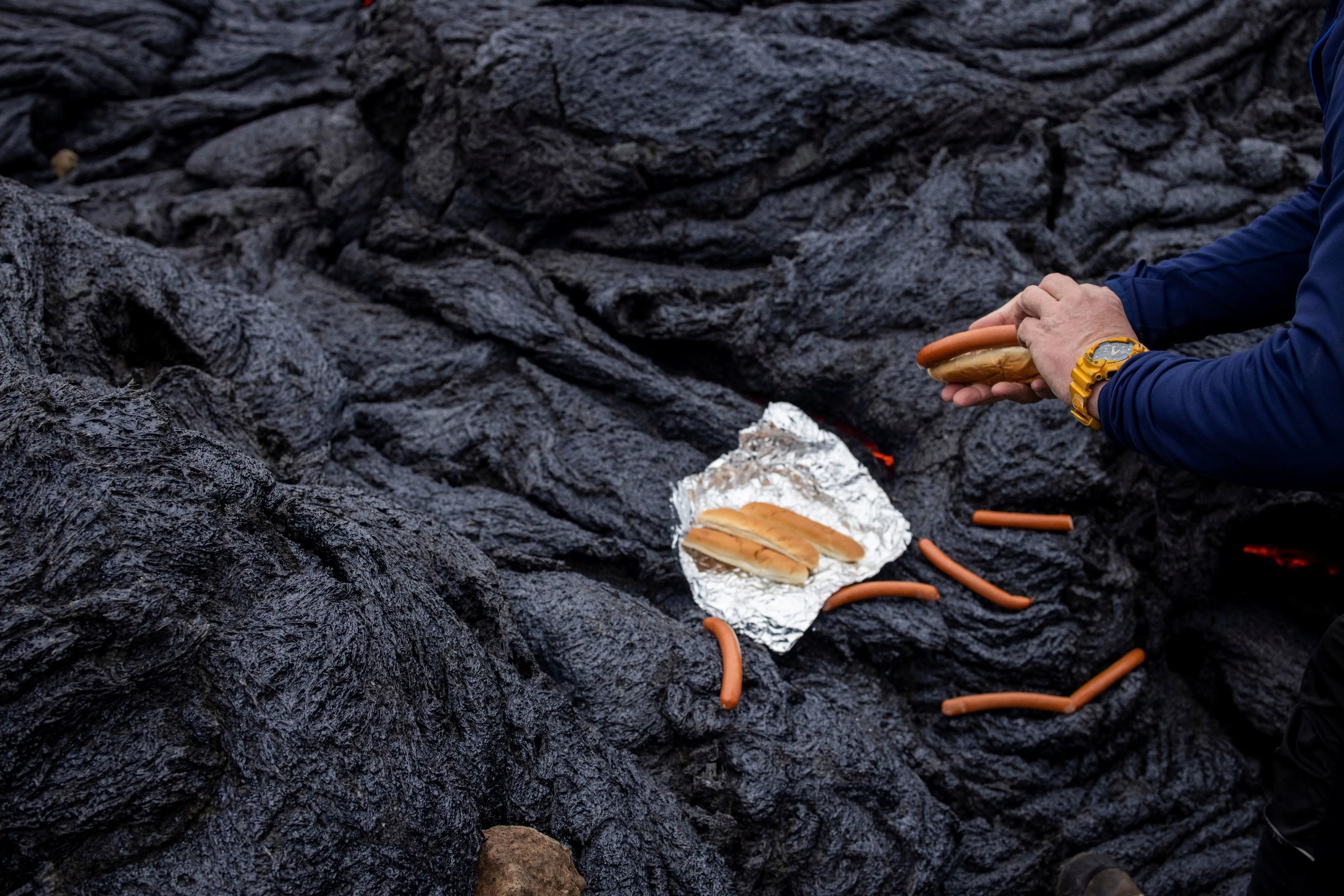 Un hombre prepara perritos calientes en el lugar volcánico de la península de Reykjanes tras la entrada en erupción 2 días antes en Islandia el 21 de marzo.