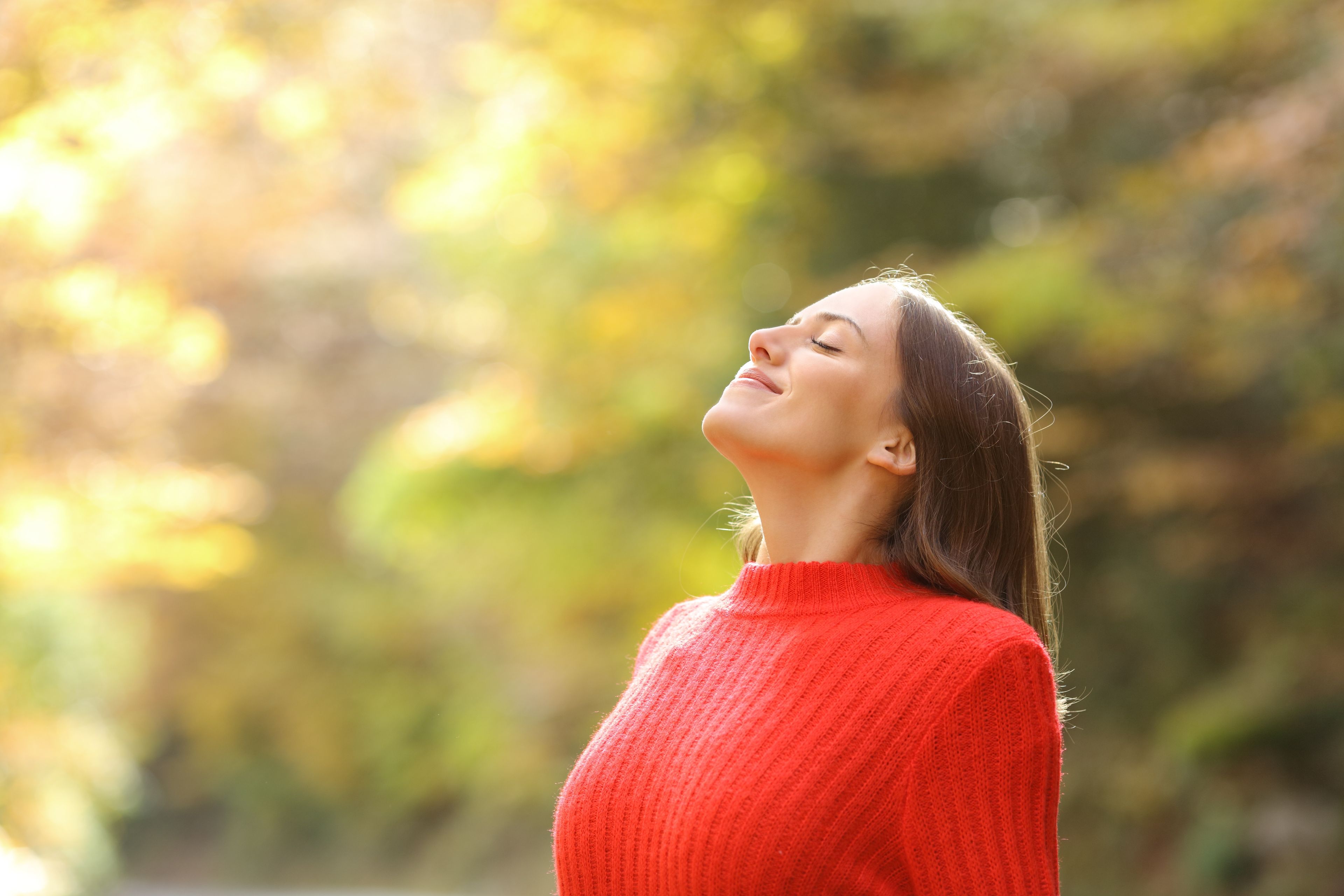 Mujer de rojo respirando aire fresco en otoño en un bosque