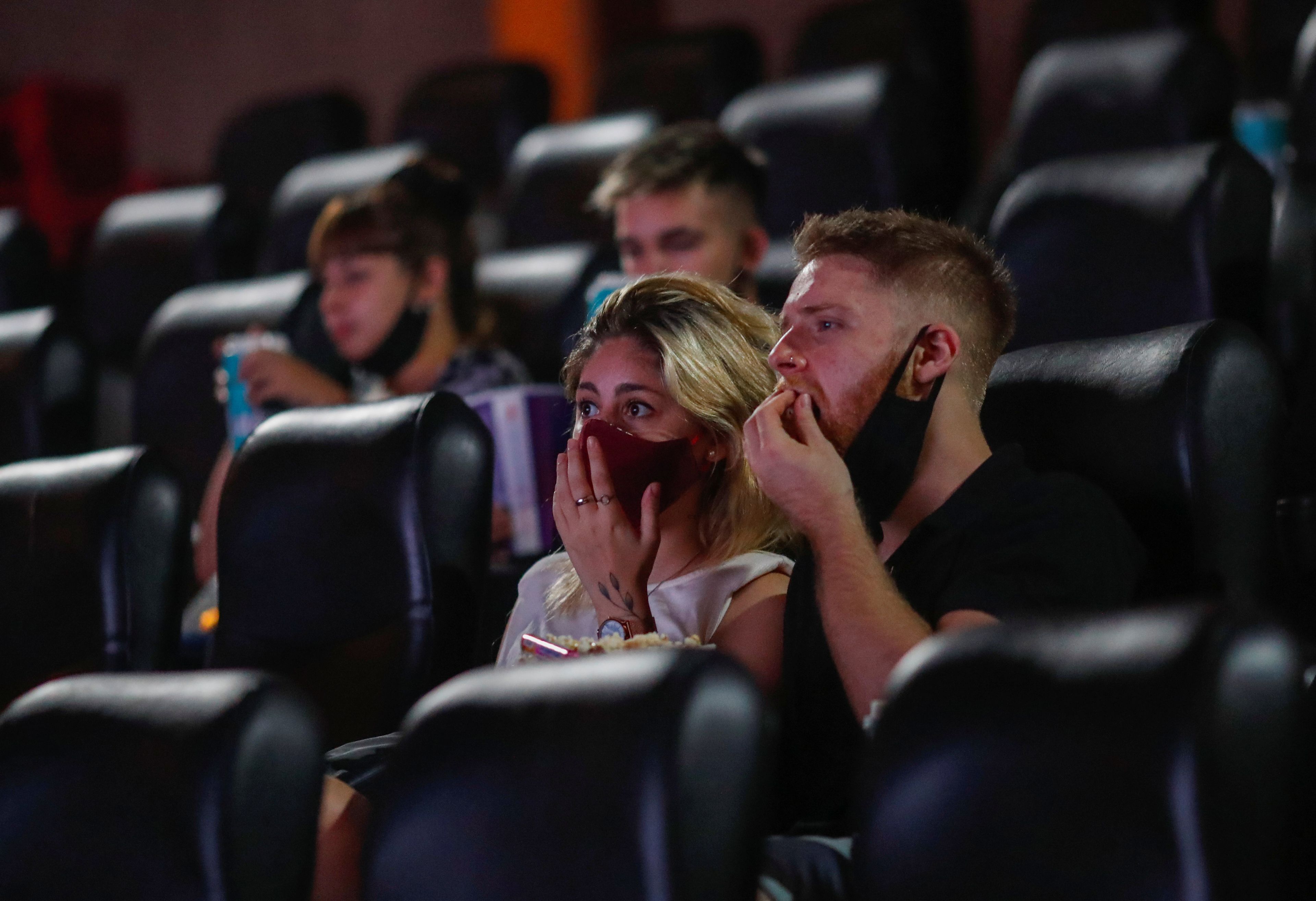 Una pareja come palomitas dentro de una sala de cine