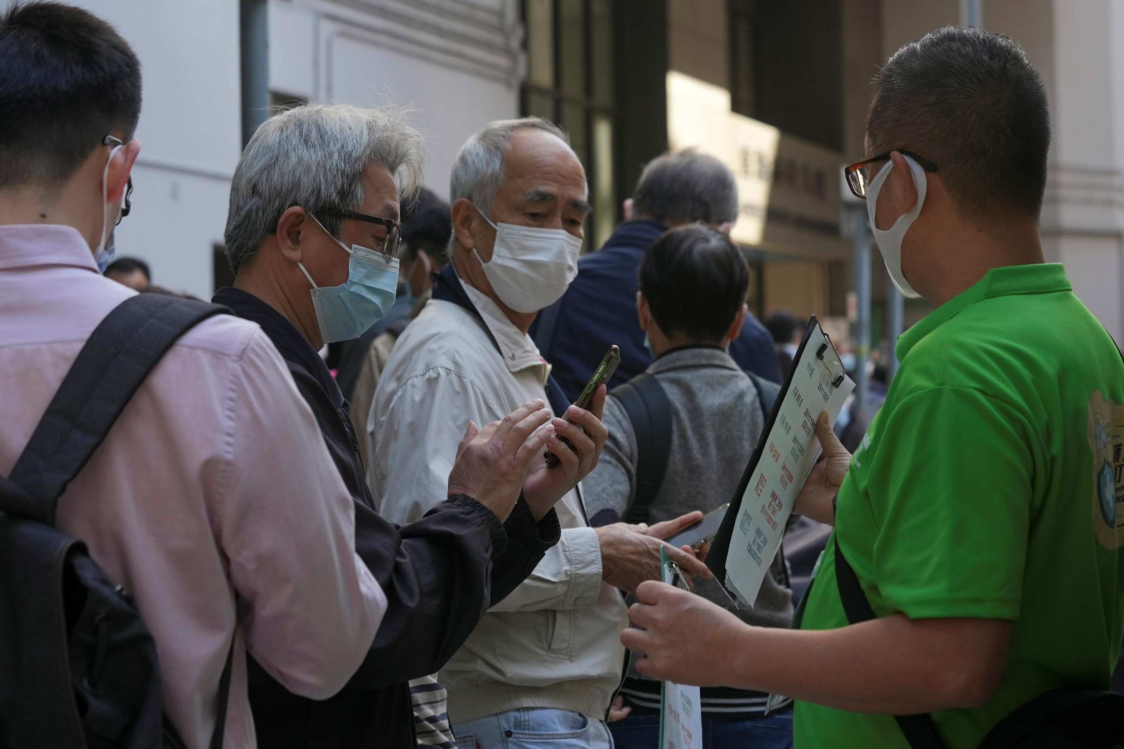Varias personas hacen cola fuera de un centro de vacunación comunitario en Hong Kong.