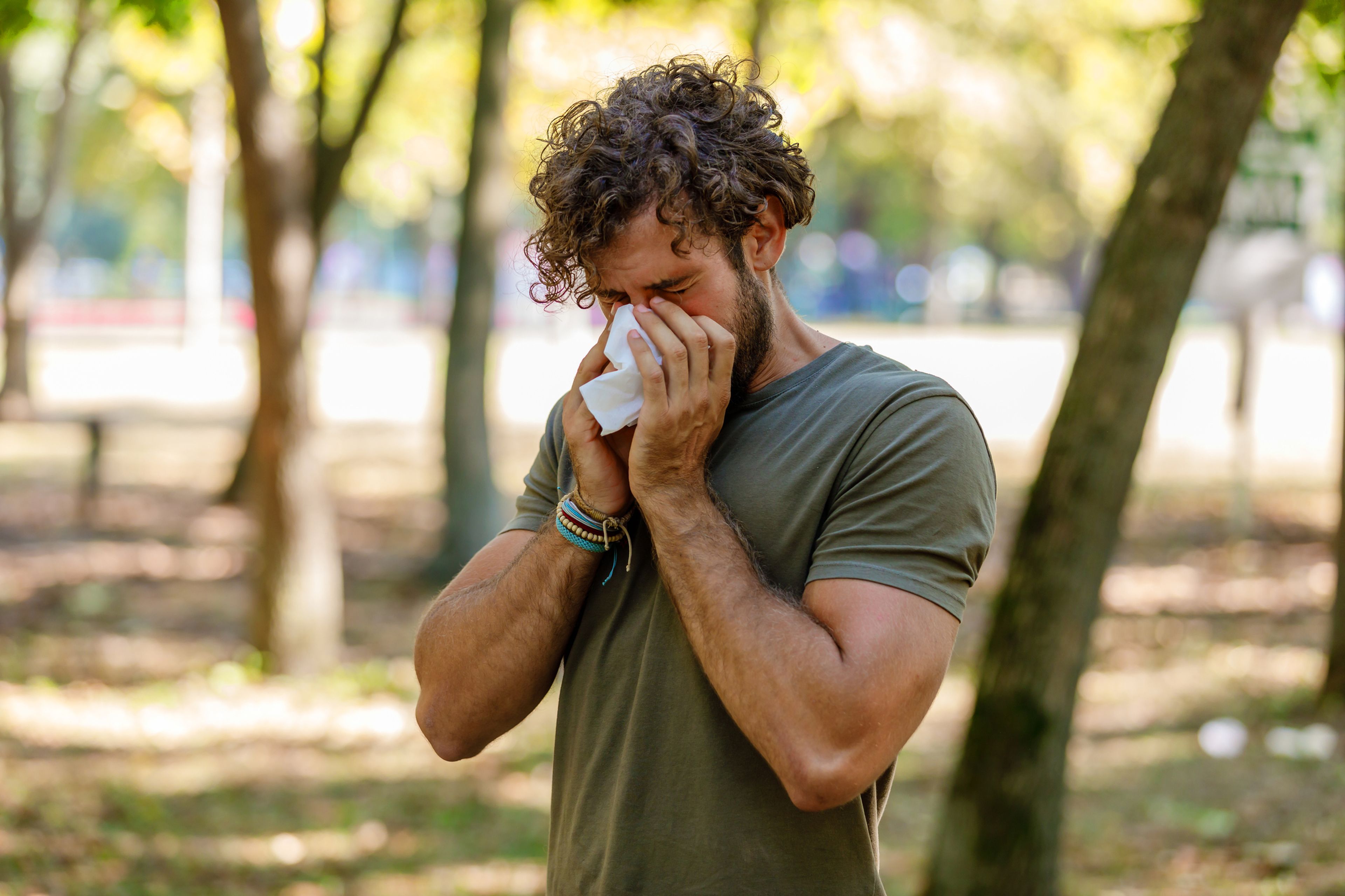 Hombre estornudando en un parque
