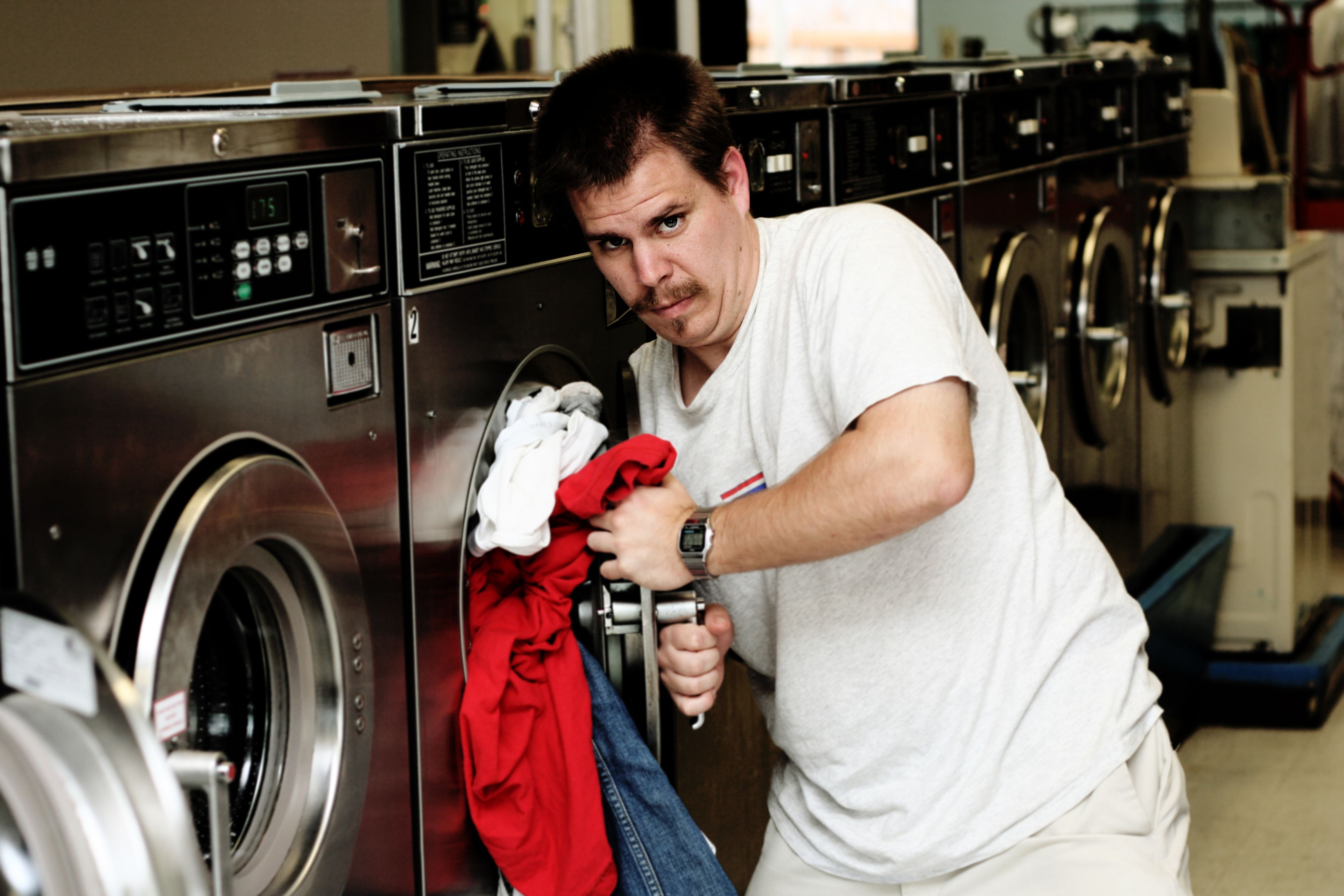Un hombre intenta cerrar una lavadora.