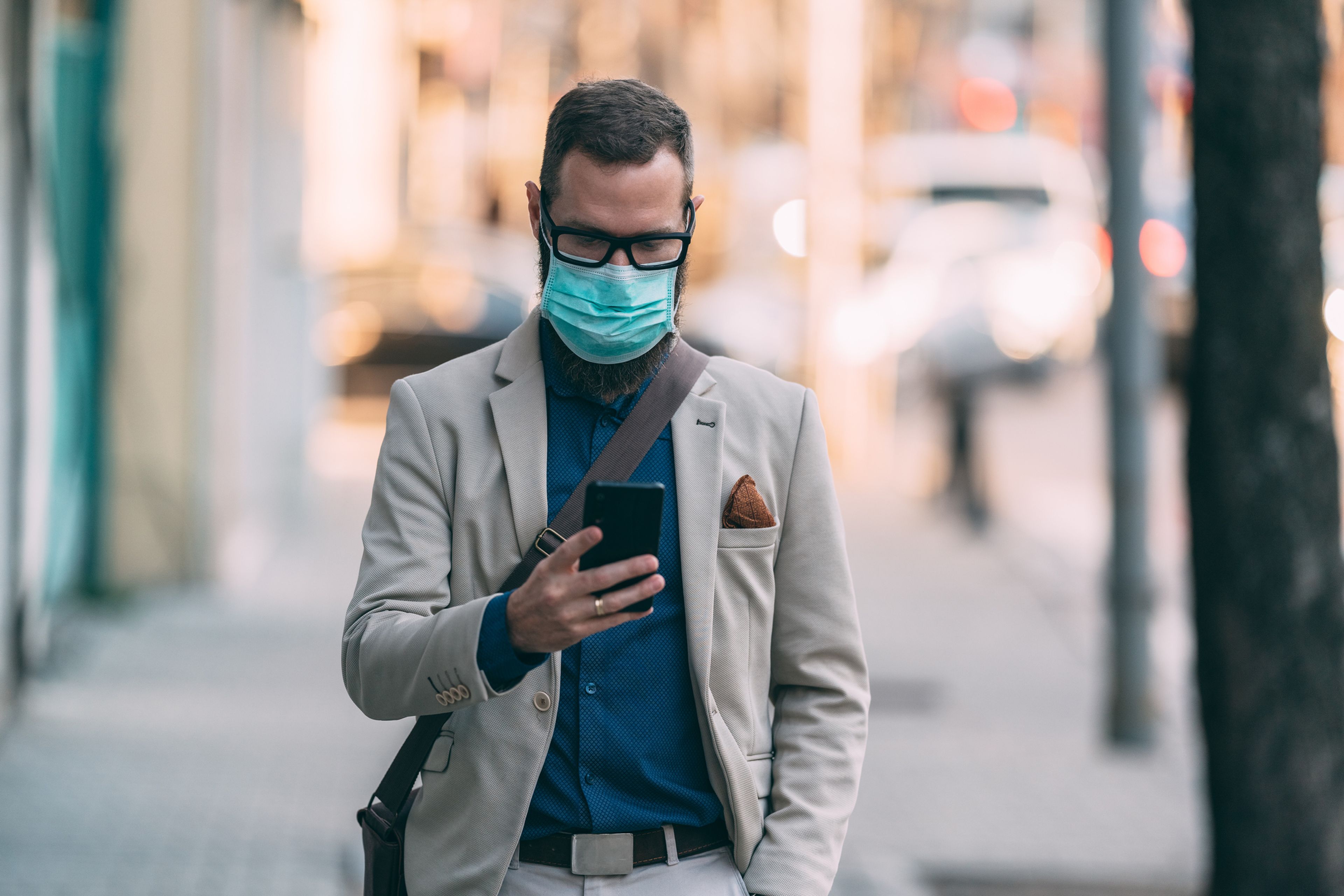 Un hombre con mascarilla mirando el móvil