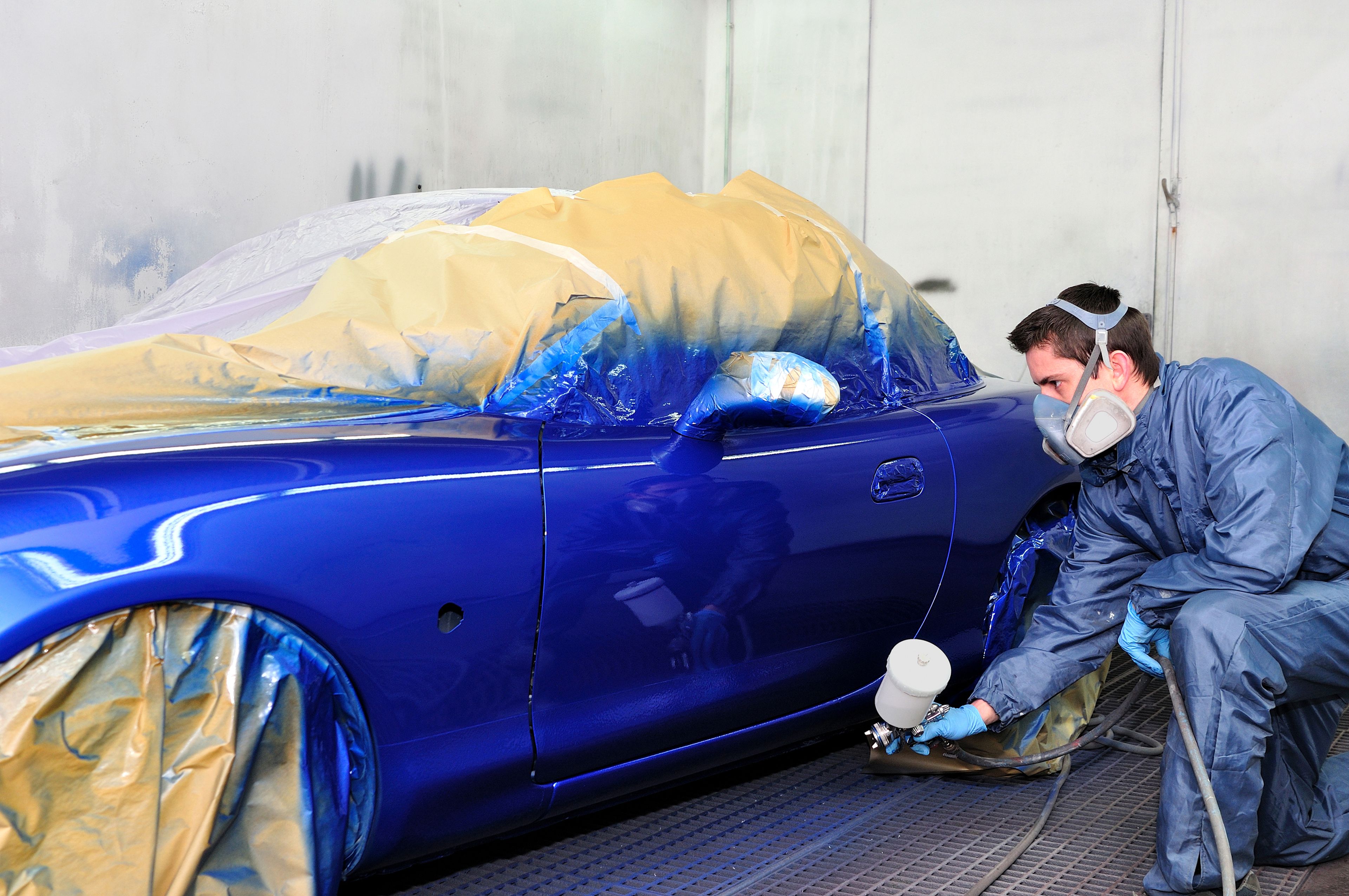 Un mecánico pintando un coche de azul