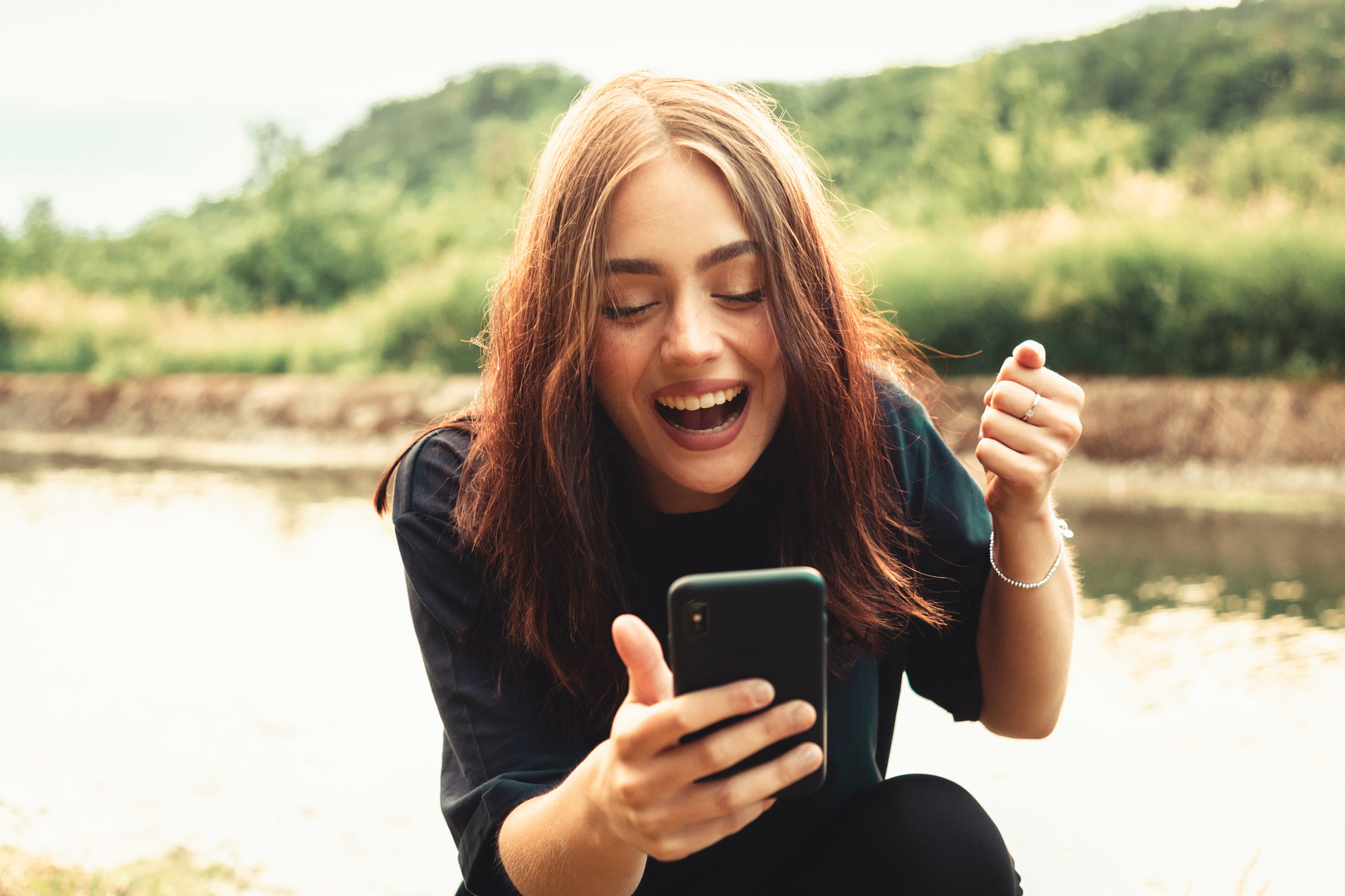 Una mujer sonriendo mirando el móvil