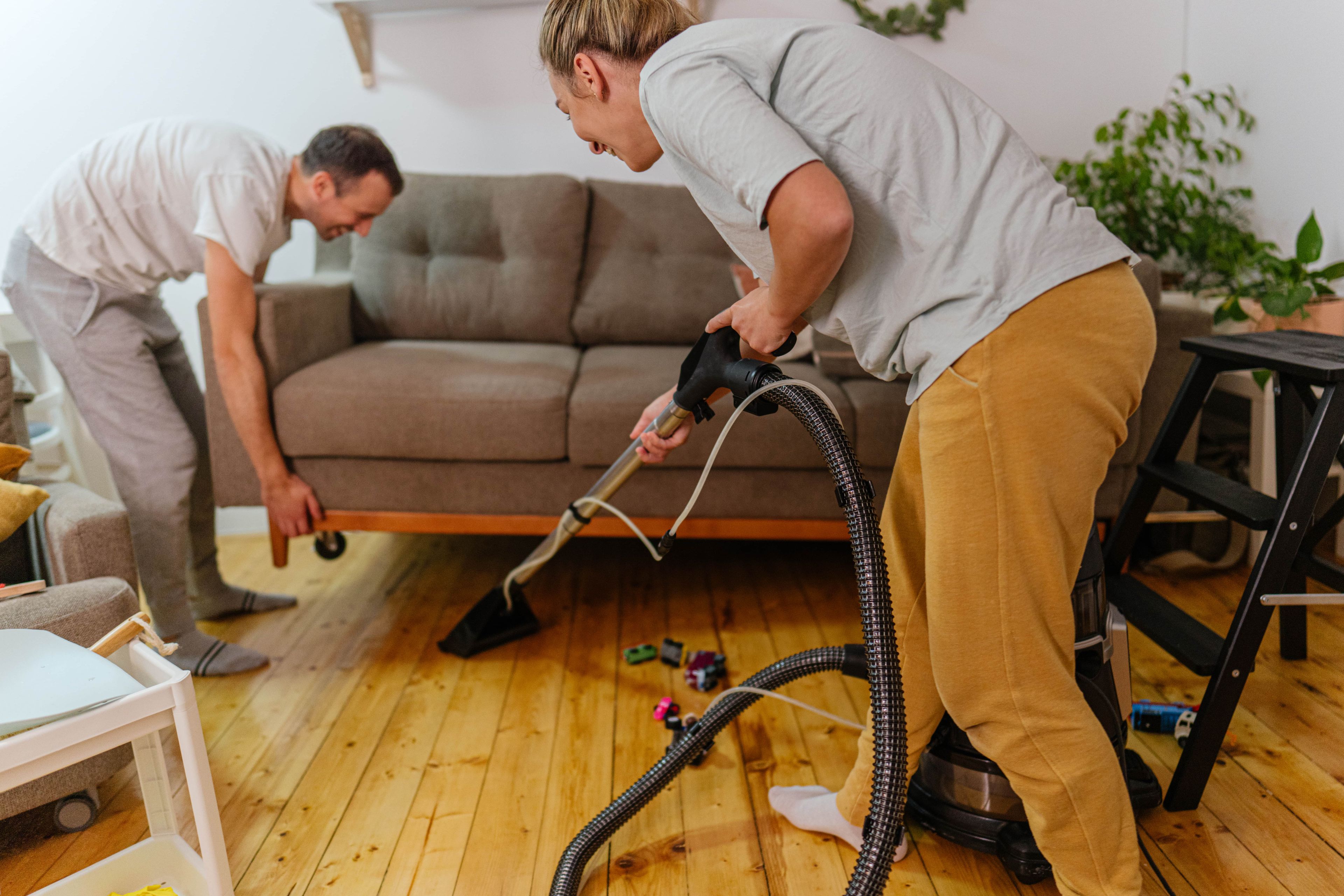 Una pareja limpiando la casa con aspiradora